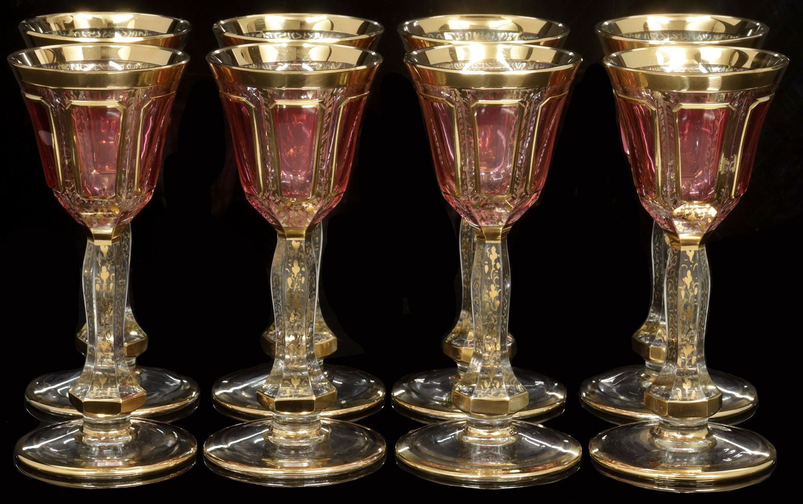 (8) VENETIAN SALVADORI MOSER-STYLE CRANBERRY CABOCHON CORDIAL GLASSES: (lot of 8) Italian parcel-gilt cabochon cordial goblets, Salvadori, Venice, 1984, each in the manner of Moser, narrow bowl with six windows, surrounded by gilt foliates and patterning on clear ground,