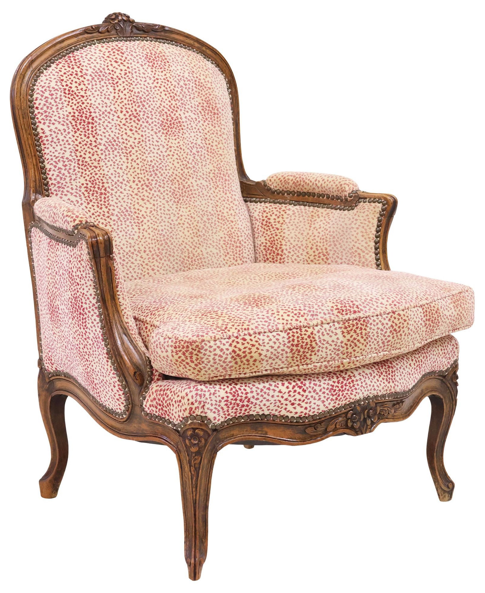 FRENCH LOUIS XV STYLE UPHOLSTERED BERGERE: French Louis XV style carved wood bergere/ armchair, late 19th c., in later red and beige dotted upholstery, with nailhead trim, removable seat cushion, rising on cabriole legs, ending on whorl feet,