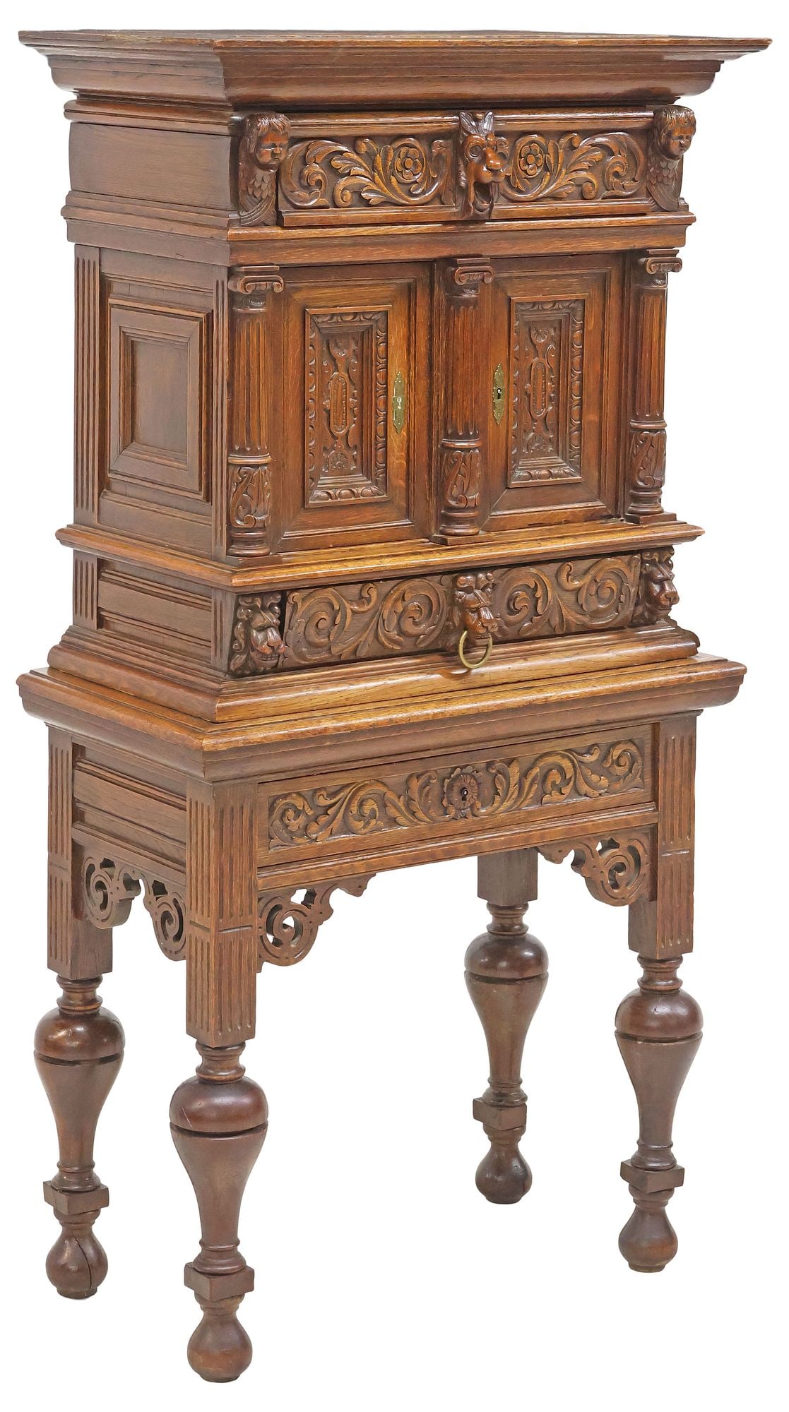 ENGLISH VICTORIAN HIGHLY CARVED OAK CREDENCE CUPBOARD: English Victorian figural carved oak credence cupboard, late 19th c., cherub masks flank the upper drawer with scrolled foliates and a central lion mask, above dual hinged doors with carved pilasters,