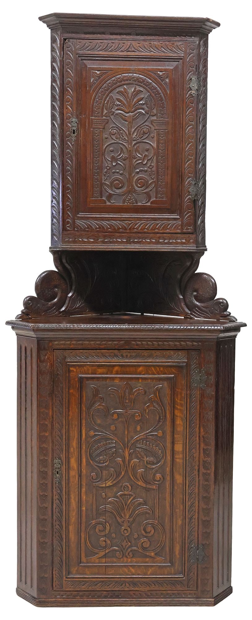 W.F. GREENWOOD & SONS ENGLISH VICTORIAN CARVED OAK CORNER CUPBOARD: English Victorian carved oak corner cupboard, W.F. Greenwood & Sons Ltd., York, 19th c., of triangular form with canted angles, upper case raised on scrolled French dolphin supports, both cabinets wit