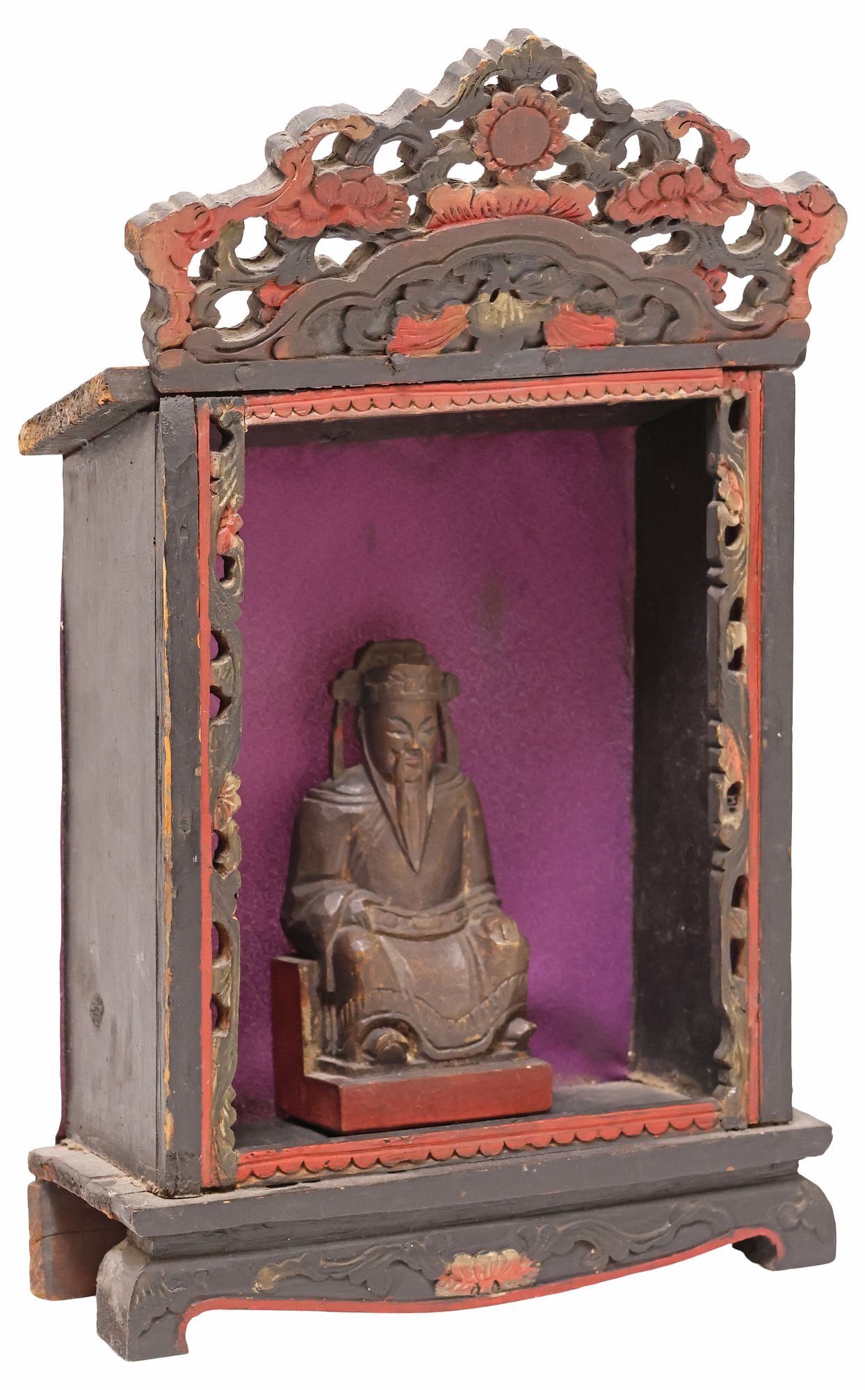 CHINESE CARVED WOOD ALTAR SHRINE WITH SEATED MALE FIGURE: Chinese carved hardwood devotional altar shrine, having pierced crest with scrolling floral motifs, over central niche, with purple fabric backing, centering seated male figure, likely a Daoist deity