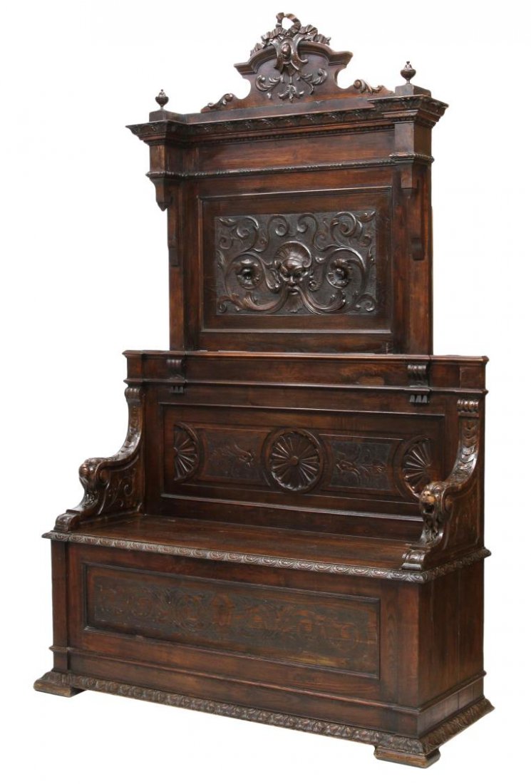 ITALIAN RENAISSANCE REVIVAL HIGHBACK HALL BENCH: Italian Renaissance Revival walnut high back hall bench, 19th c., ribbon carved crest surmounting a figural panel showing a masque amid scrolled vines, lion form armrests, lift seat revealing open sto