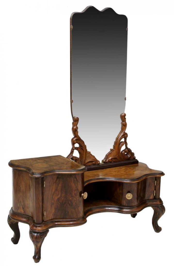 VENETIAN BAROQUE MIRRORED FIGURED WALNUT VANITY: Venetian Baroque figured walnut veneer vanity, early 20th c., the beveled mirror held by carved foliate uprights, free form two level table, above two hinged compartments, cariole legs terminate in sc