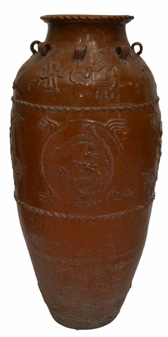 LARGE ASIAN GLAZED EARTHENWARE WATER JAR: Large Asian glazed ceramic water jar, of tapering form in a dark golden brown glaze, a writhing dragon and foliates among other auspicious symbols in relief, applied with eight ribbed looped handles,
