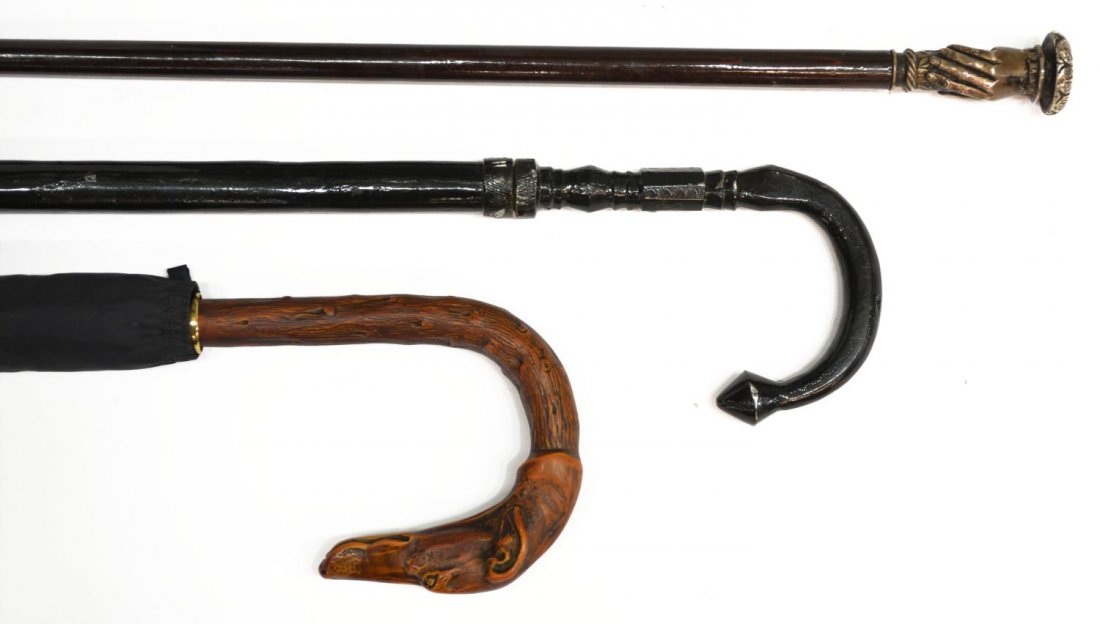 (3) SWORD CANES & HOUNDS HEAD UMBRELLA: (lot of 3) Canes and umbrella: (1) walking stick with pull out 25" clear lacquered sword blade, the case, metal handle, later black lacquer, overall: 36.5"l; (1) walking stick with pull out 11.25" fou