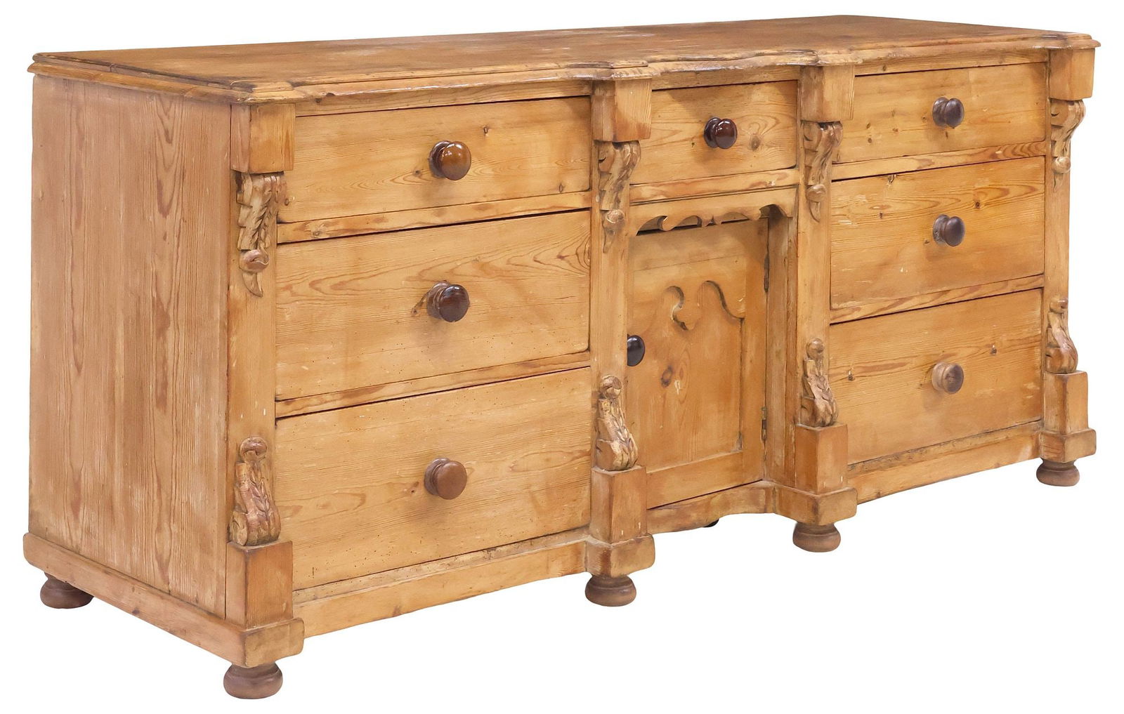 ENGLISH VICTORIAN CARVED PINE KITCHEN DRESSER: English Victorian pine kitchen dresser, 19th c., having shaped top with molded edge, fitted with seven drawers, and central paneled cabinet enclosing fixed-height shelf, framed by foliated scroll