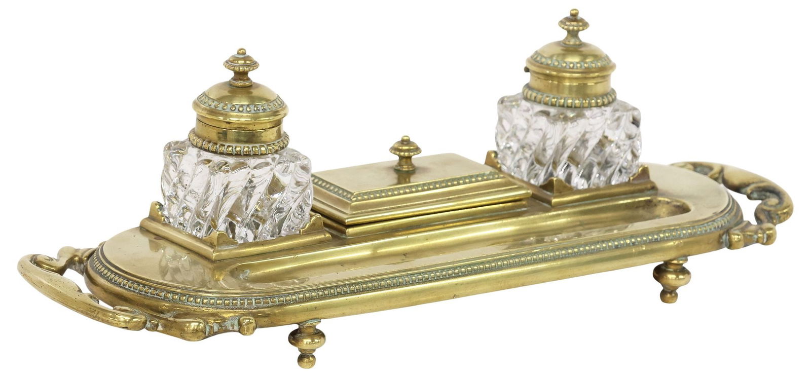 WILLIAM TONKS & SONS VICTORIAN BRASS DOUBLE-INKWELL DESK STAND: English Victorian brass double-inkwell desk stand, William Tonks & Sons, late 19th/ early 20th c., ovoid stand on turned-form feet, with beaded trim and scrolled handles, flanking two molded glass ink