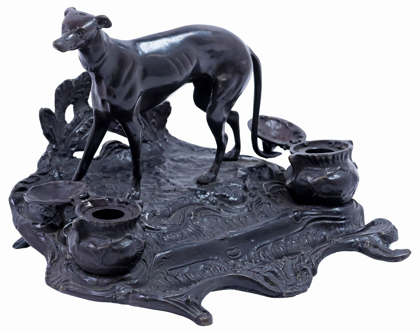 AFTER P.J. MENE (D.1879) PATINATED BRONZE DOUBLE INKWELL / DESK STAND: Patinated bronze double-inkwell desk stand, early 20th c., signed in cast after P.J. Mene (Pierre-Jules Mene, French, 1810-1879), surmounted by a greyhound in full relief, flanked by dual fixed inkwel