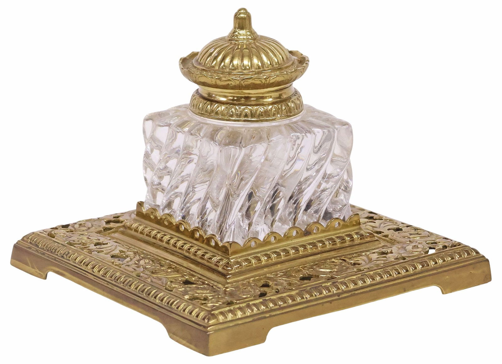 ENGLISH FLORAL OPENWORK GILT-METAL INKWELL / DESK STAND: English gilt-metal and glass desktop inkwell, early 20th c., having square stand on bracket feet, with pierced floral motif, supporting large molded glass inkwell, with finialed domed metal lid, stamp