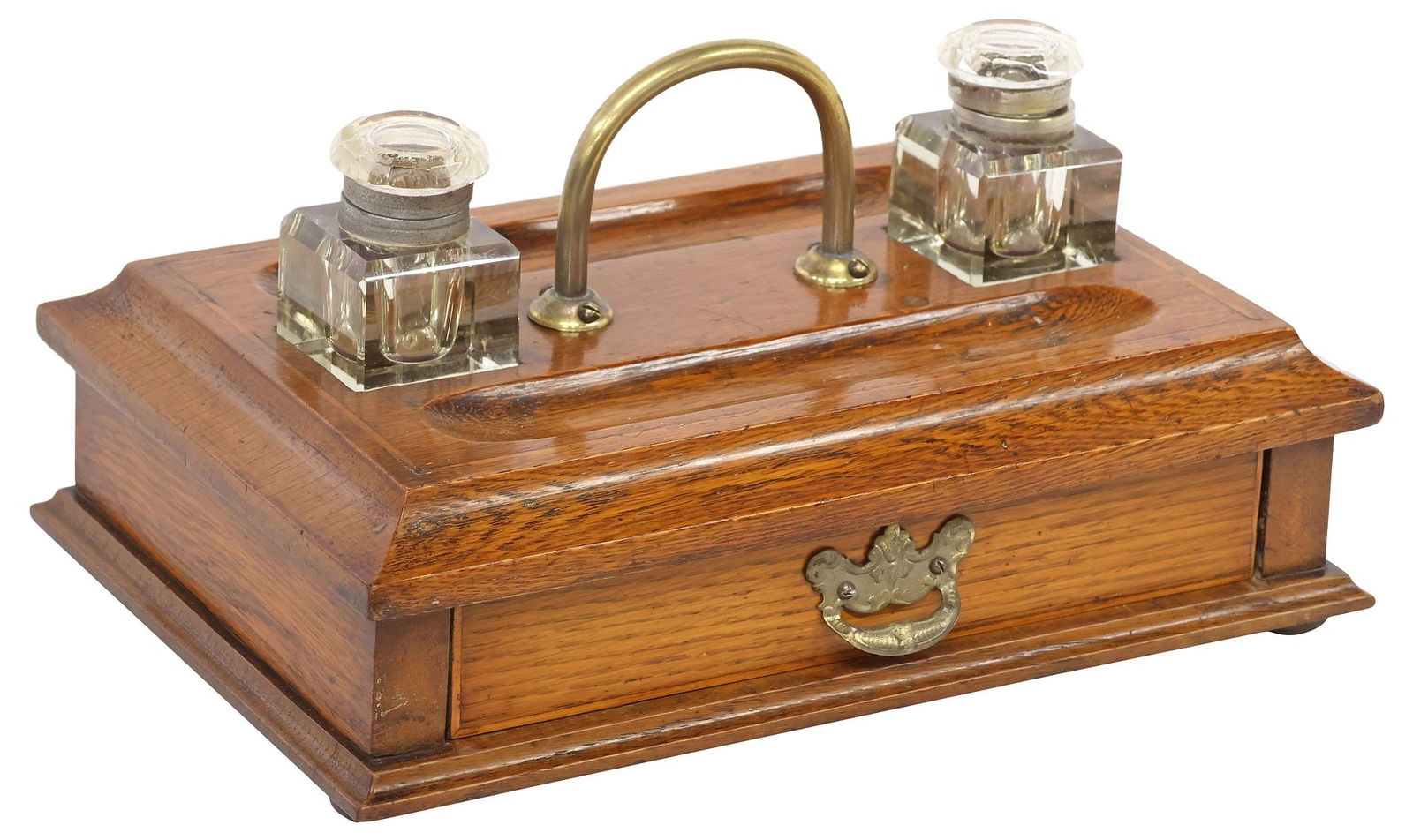 ENGLISH BRASS MOUNTED & OAK DOUBLE INKWELL DESK STAND: English oak and brass inkwell desk stand, early 20th c., rectangular stand fitted with single frontal drawer, dual writing instrument receptacles, retaining two glass inkwells, central brass handle, a