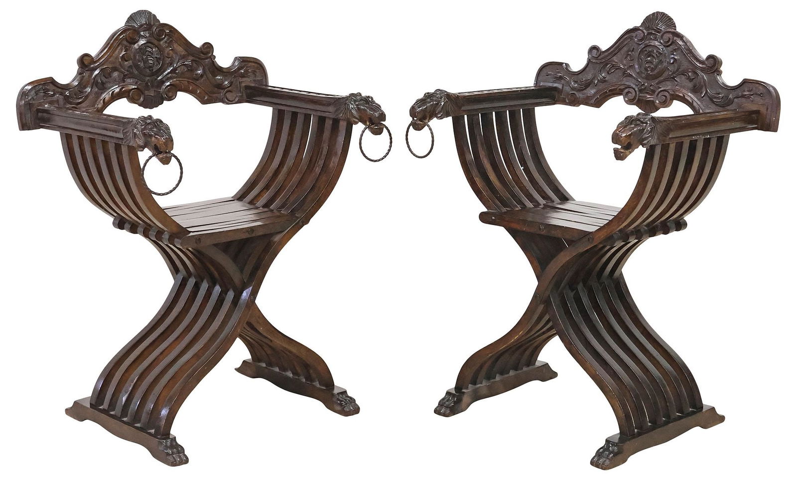 (2) ITALIAN RENAISSANCE REVIVAL WALNUT SAVONAROLA CURULE CHAIRS: (pair) Italian Renaissance Revival carved walnut Savonarola chairs, early 20th c., each having fanned crest over foliated scrollwork, slatted frame, lion mask hand holds with captured iron rings, risi