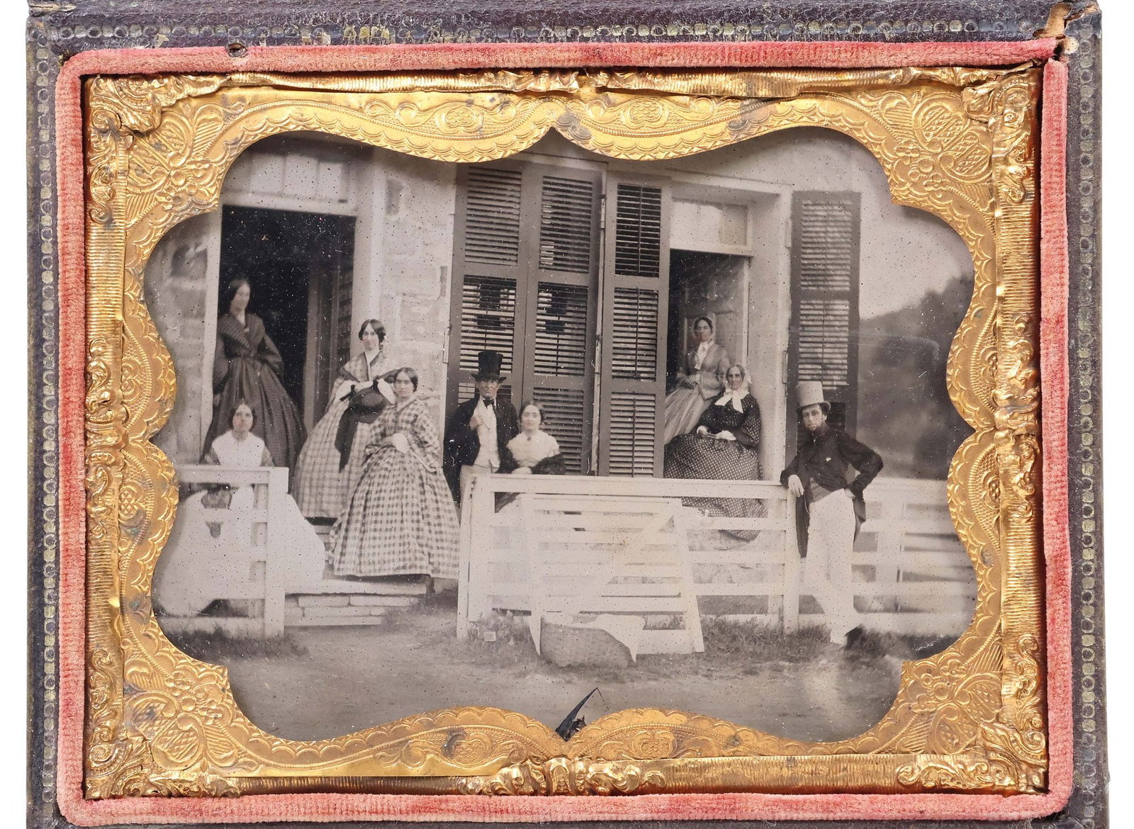 CASED CIVIL WAR-ERA QUARTER PLATE AMBROTYPE PHOTO, GROUP PORTRAIT: Cased quarter-plate ambrotype photograph, 19th c., depicting nine people in Civil War-era dress, standing and seated along a porch, with masonry house facade in background, housed in a hinged and