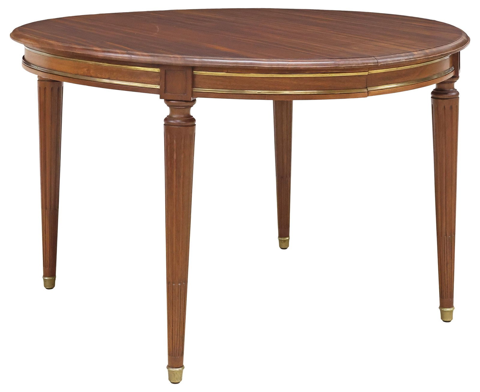 FRENCH LOUIS XVI STYLE MAHOGANY EXTENSION DINING TABLE: French Louis XVI style mahogany extension dining table, 20th c., circular top, above gilt-metal trimmed apron, tapering fluted legs ending on brass cap feet, one side of table lacking lower metal trim
