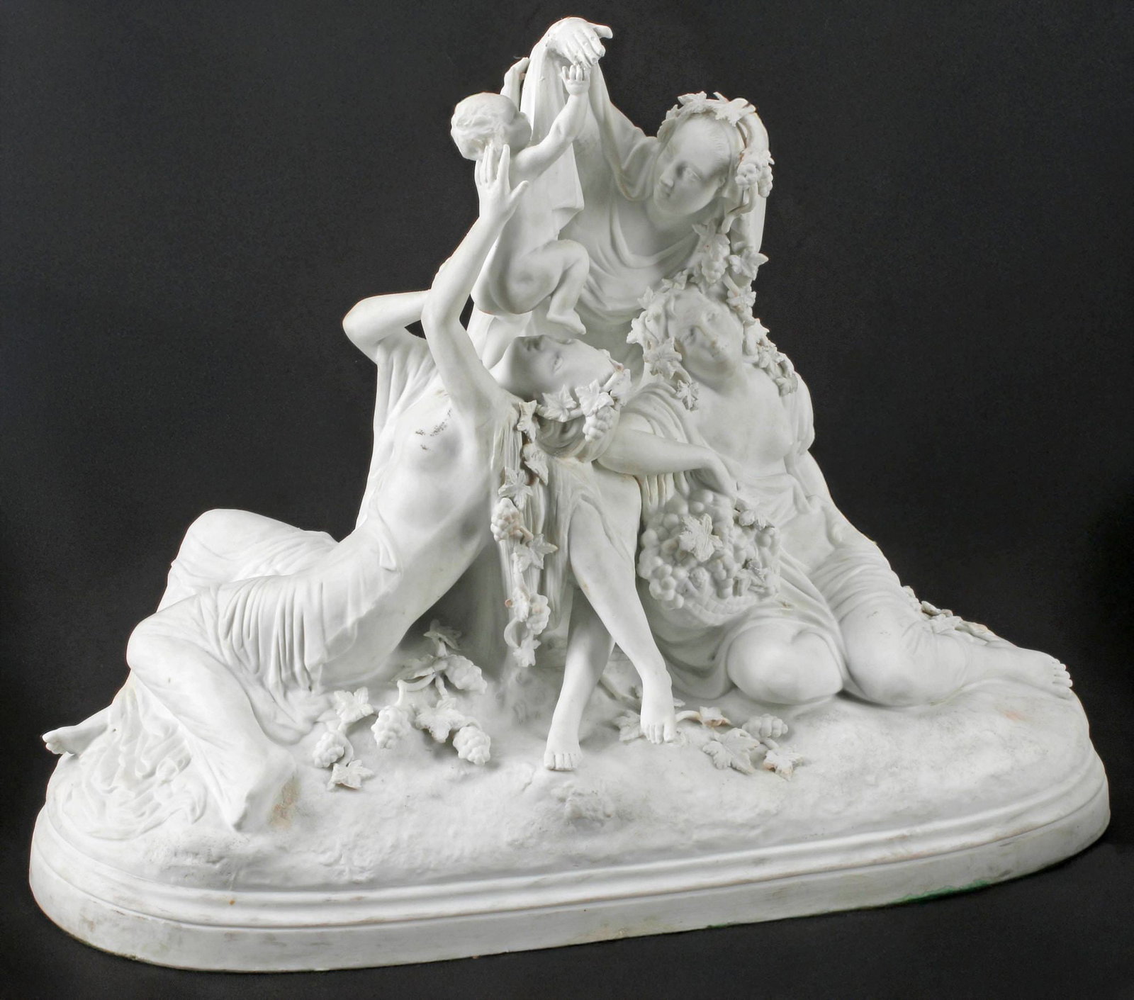 FRENCH SEVRES STYLE BISCUIT PORCELAIN BACCHANTE FIGURAL GROUP: French Sevres style bisque porcelain Bacchic figural group, 19th c., depicting the infant Bacchus encircled by maiden attendants, in draped garments adorned with grape vines, on a naturalistic