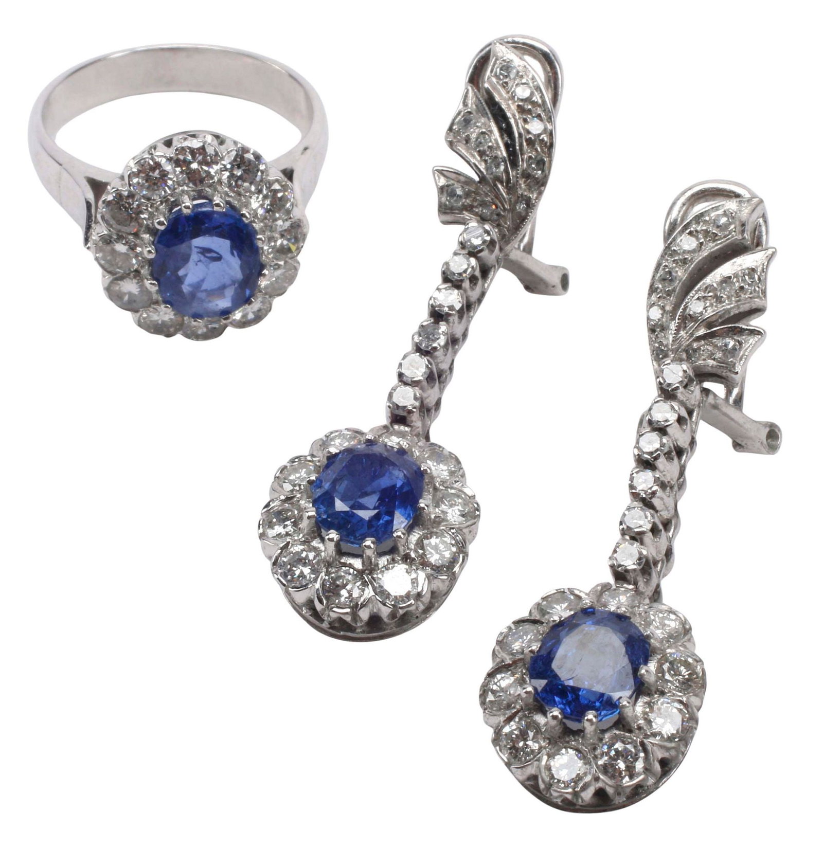 (2) ESTATE 10KT WHITE GOLD, DIAMOND & SAPPHIRE JEWELRY SUITE: (lot of 2) Estate 10kt white gold (tested) and gemstone demi-parure, including: (pair) drop earrings with foliate surmounts, each with an oval-cut blue sapphire, approx 2.70cttw, (twenty-six) round-cu