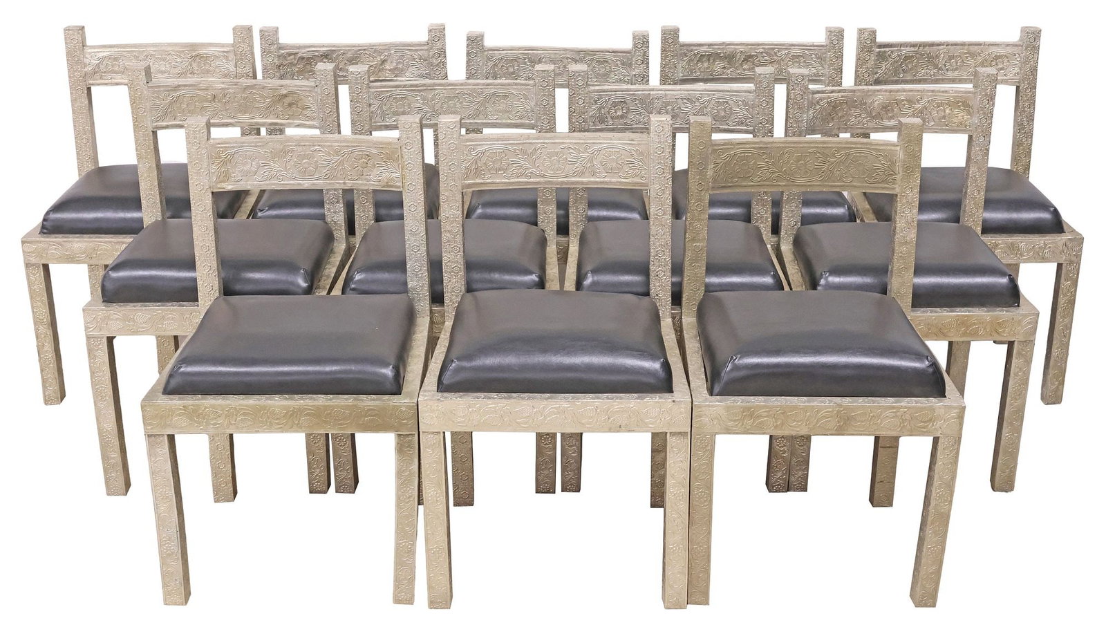 (12) ANGLO-INDIAN STYLE SILVERED METAL-CLAD & UPHOLSTERED DINING CHAIRS: (lot of 12) Anglo-Indian style silvered metal-clad side chairs, each having padded seat in black leather upholstery, with repousse scrollwork, approx 35.5"h, 21"w, 20"d, seat height: approx 21"h