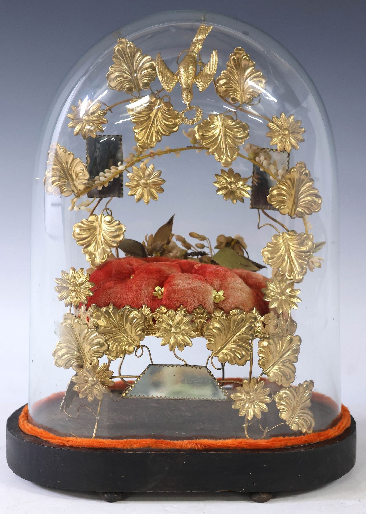 FRENCH GLOBE DE MARIEE / BRIDE'S GLOBE IN GLASS CLOCHE: French globe de mariee/ bride's globe, late 19th c., glass cloche/ dome on ebonized base, enclosing floral gilt metal frame, on red tufted cushion, approx 14.75"h, 10.5"w, 6.5"d, 3.25lbs