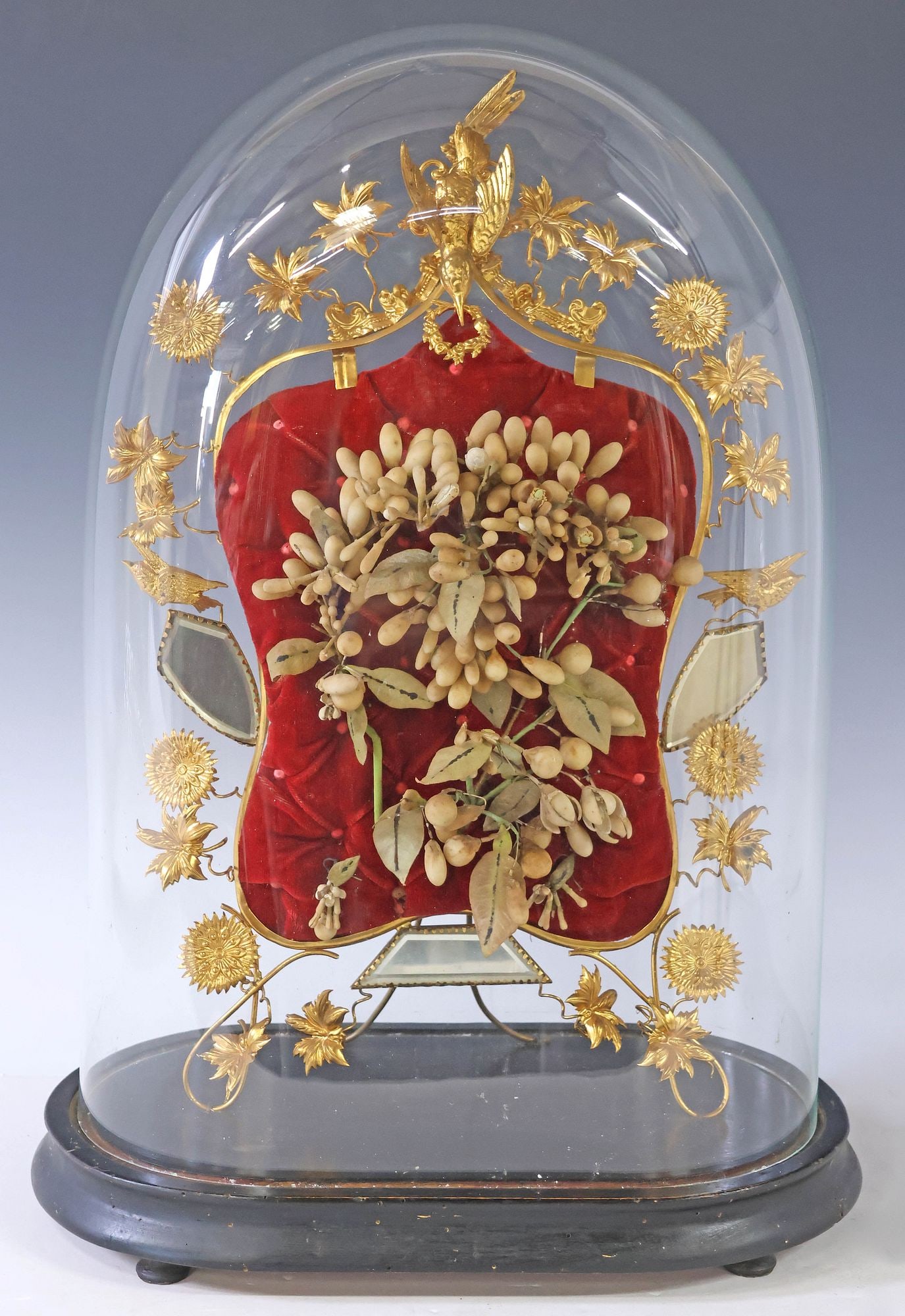 FRENCH GLOBE DE MARIEE / BRIDE'S GLOBE IN GLASS CLOCHE: French globe de mariee/ bride's globe, late 19th c., glass cloche/ dome on ebonized base, enclosing gilt metal frame, with silk flowers on red tufted cushion, approx 19.5"h, 13"w, 7.5"d, 6lbs