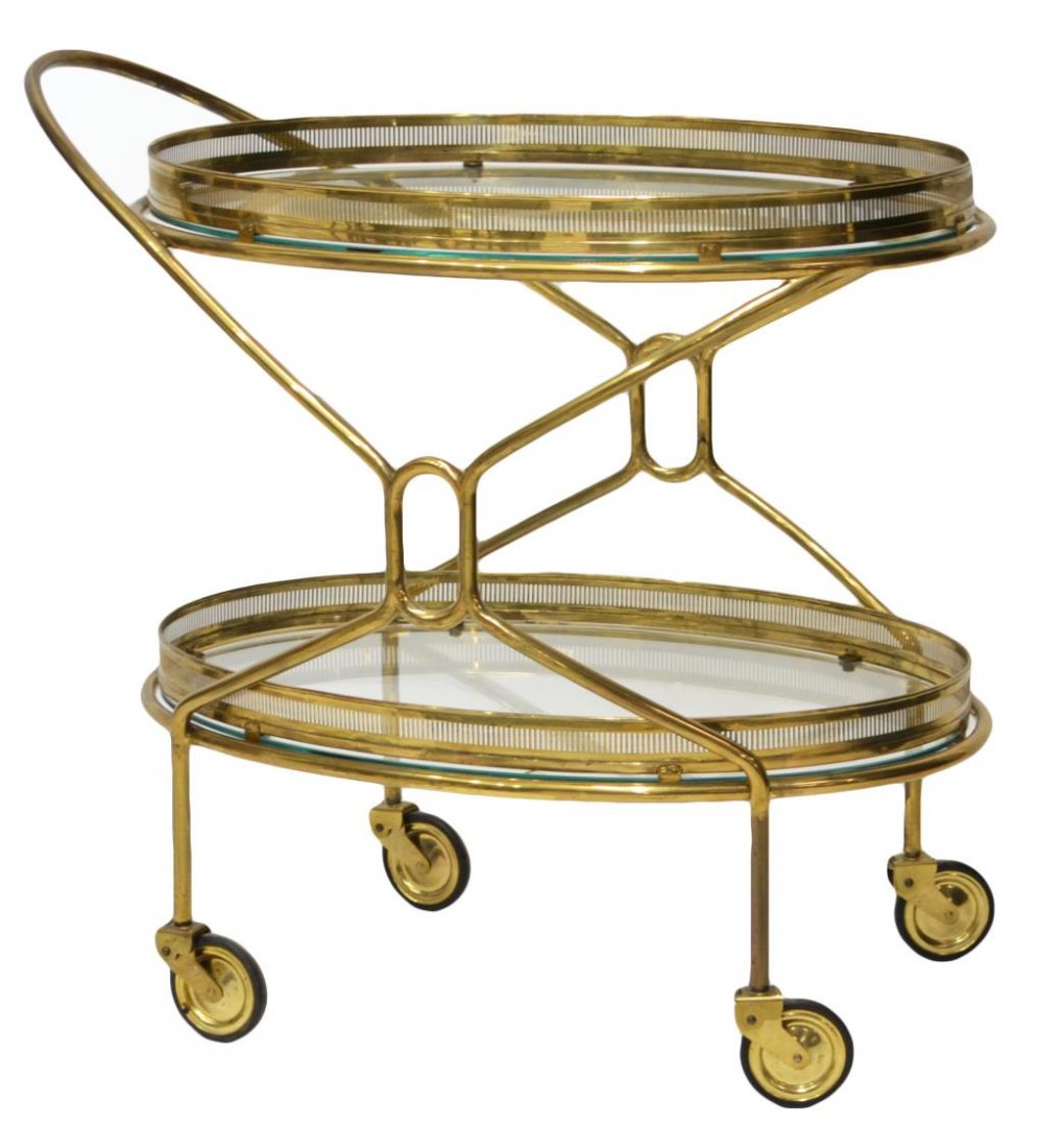 MODERN GILT BRASS & GLASS TIERED SERVICE CART: Modern brass and glass service trolley, c. 1960’s, two galleried tiers with oval glass inserts, moving on large round wheels, frame joining contiguous curved handle, approx 27”h, 28.5”w, 17.25��