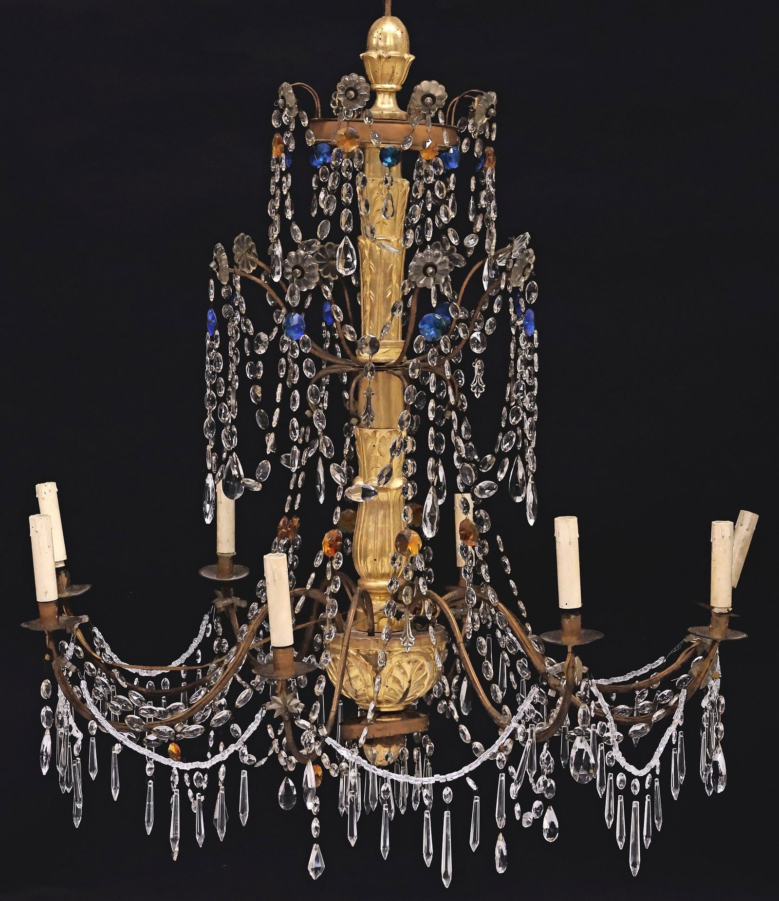 ITALIAN GILTWOOD & COLORED CRYSTAL 8-LIGHT CHANDELIER: Italian giltwood eight-light chandelier, early 20th c., foliated central standard issuing iron appendages and arms, hung with crystal beaded swags, accented by blue and amber colored medallions, scrol