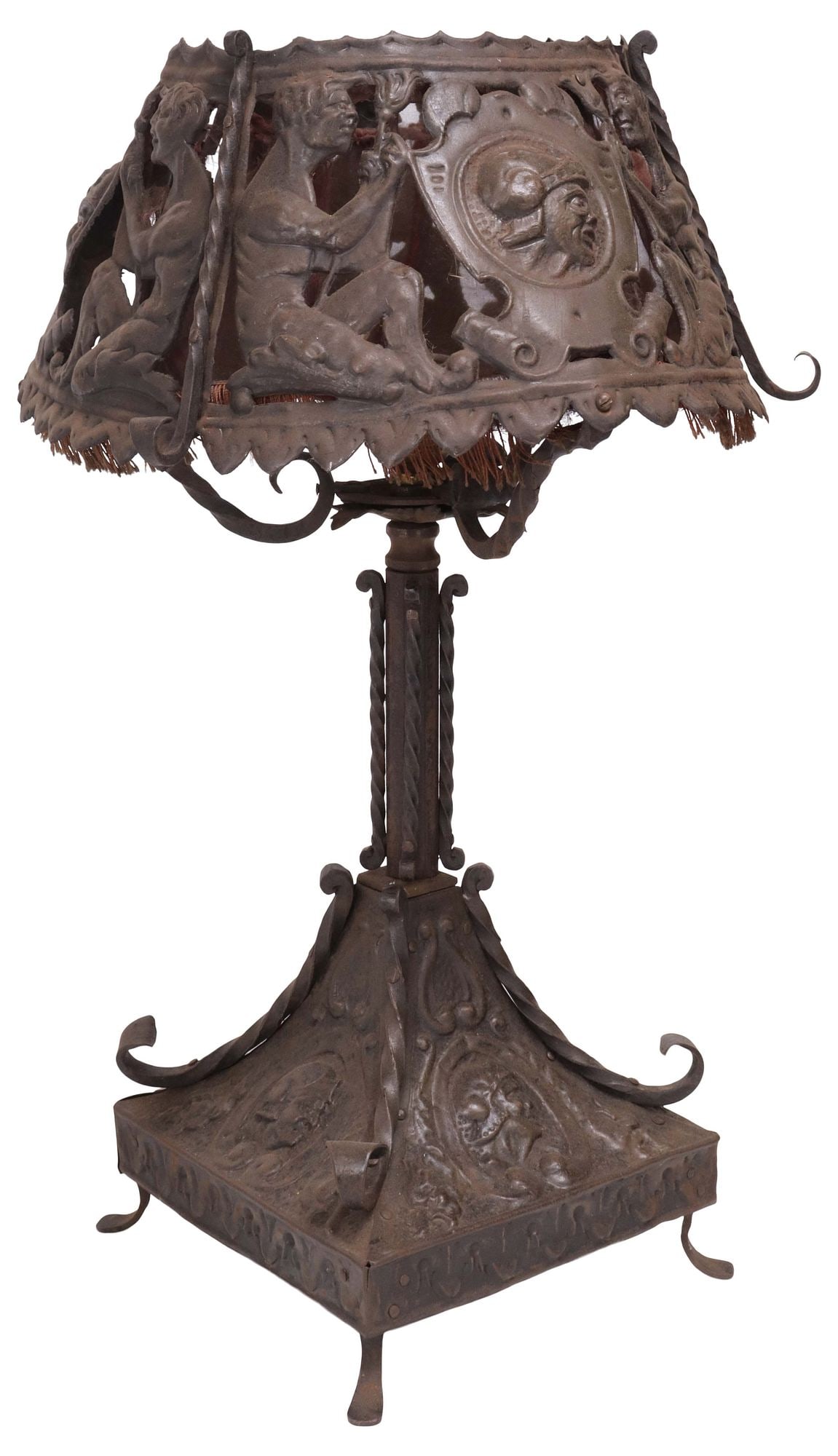 SPANISH RENAISSANCE REVIVAL CAST IRON 1-LT TABLE LAMP: Spanish Renaissance Revival cast iron single-light table lamp, early 20th c., pierced shade with shield-form portrait plaques flanked by kneeling figures, worn fabric lining, over columnar standard wi