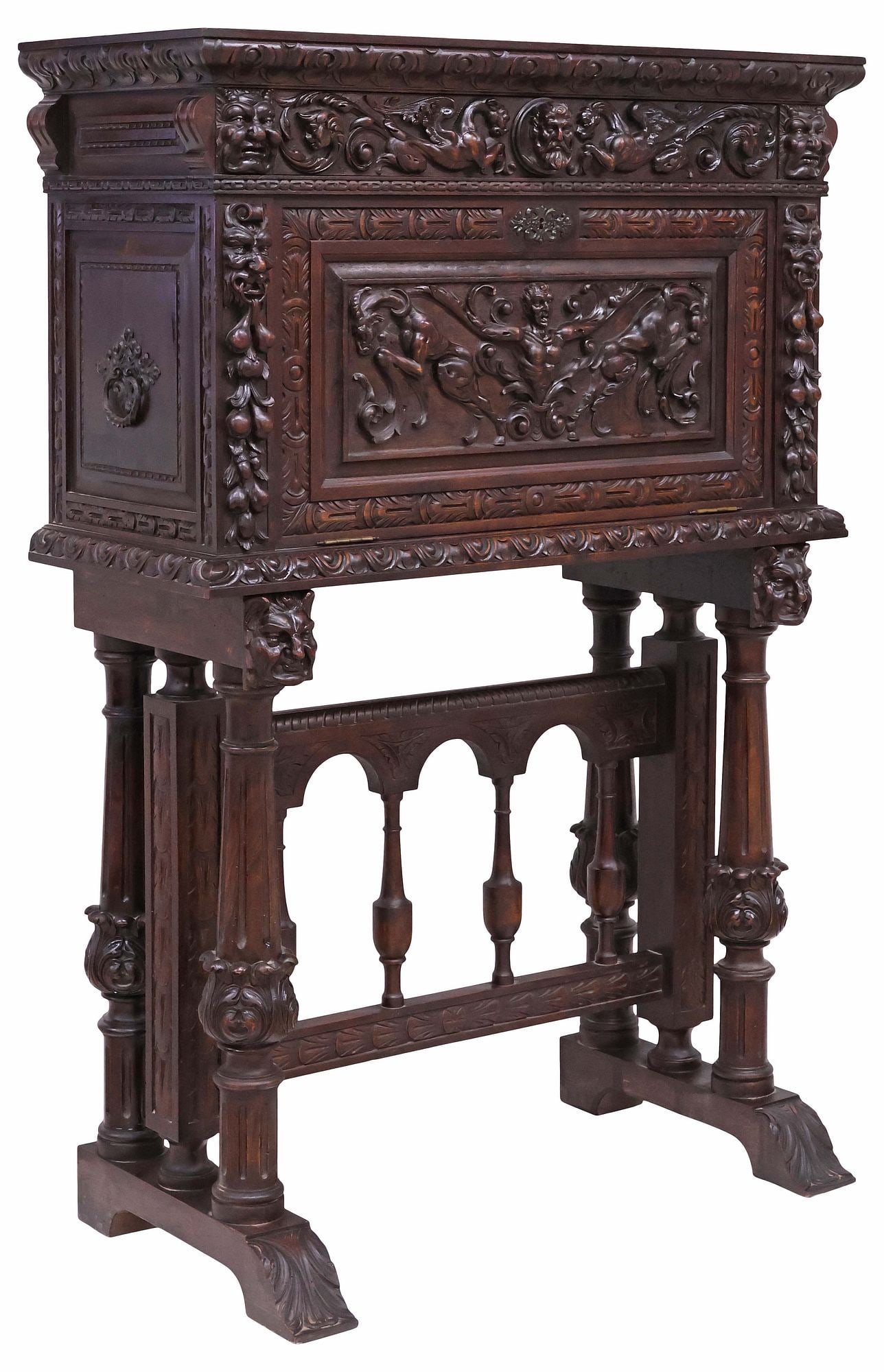 SPANISH RENAISSANCE REVIVAL CARVED WALNUT VARGUENO ON STAND: Spanish Renaissance Revival bargueno/ vargueno cabinet on stand, early 20th c., ornately carved with figures, grotesque masks, and mythical beasts in relief, the frieze fitted as a drawer with central