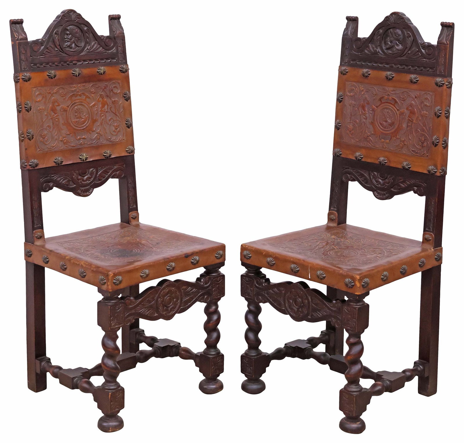 (2) SPANISH RENAISSANCE REVIVAL LEATHER & WALNUT SIDE CHAIRS: (pair) Spanish Renaissance Revival carved walnut hall chairs, 19th c., each in worn tan leather upholstery, with embossed portrait roundel framed by scrolling foliates and allegorical figures, finishe