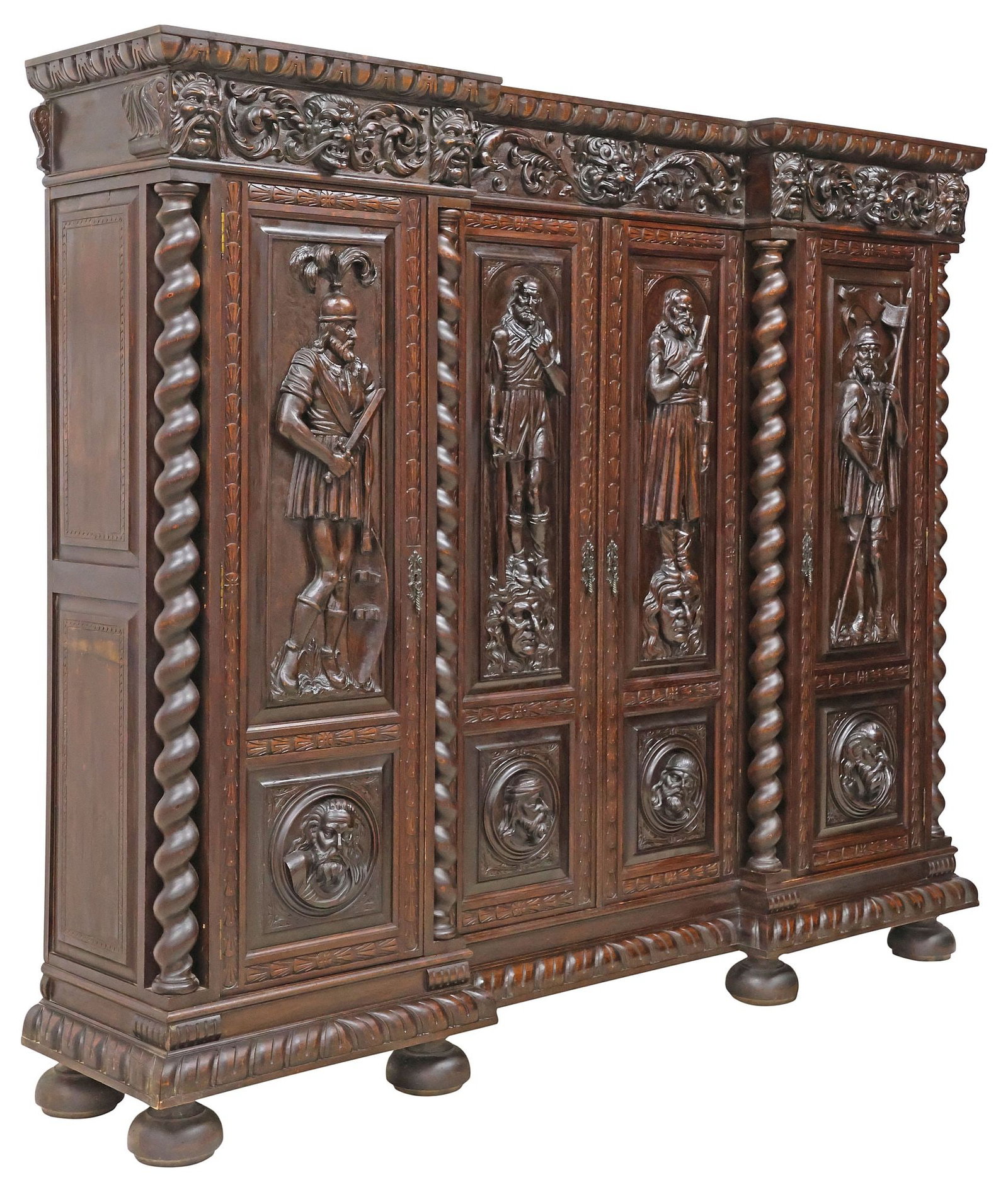 FINE SPANISH RENAISSANCE REVIVAL HIGHLY-CARVED FIGURAL CARVED WALNUT BOOKCASE: Exceptional Spanish Renaissance Revival carved walnut bookcase, late 19th c., having egg-and-dart cornice and scrolling foliate frieze with grotesque masks, above four paneled cabinet doors, each with