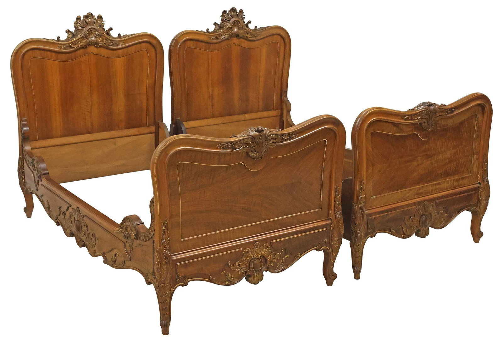 (2) FRENCH LOUIS XV STYLE PARCEL-GILT & CARVED WALNUT ALCOVE BEDS: (pair) French Louis XV style carved walnut alcove beds, early 20th c., having fanned scrolling foliate crests, above paneled headboards, each with one shaped side rail with raised rocaille, the other 