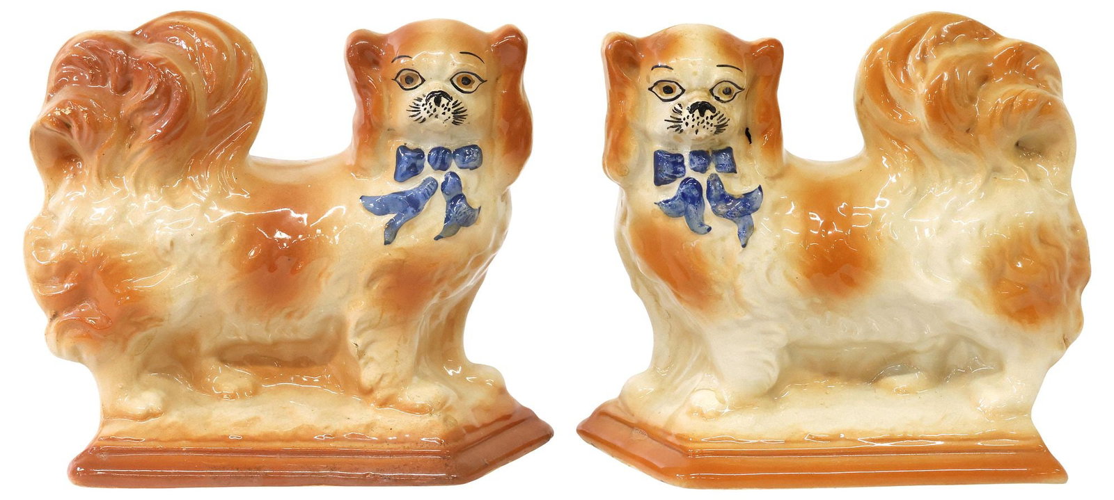 (2) ENGLISH STAFFORDSHIRE PEKINGESE MANTEL DOGS: (pair) English Staffordshire mantel dogs, 20th c., modeled as Pekingese, with painted features and blue-glazed bow tie, standing atop a lozenge-shaped base, worn registry stamp underfoot, approx 7.5"h