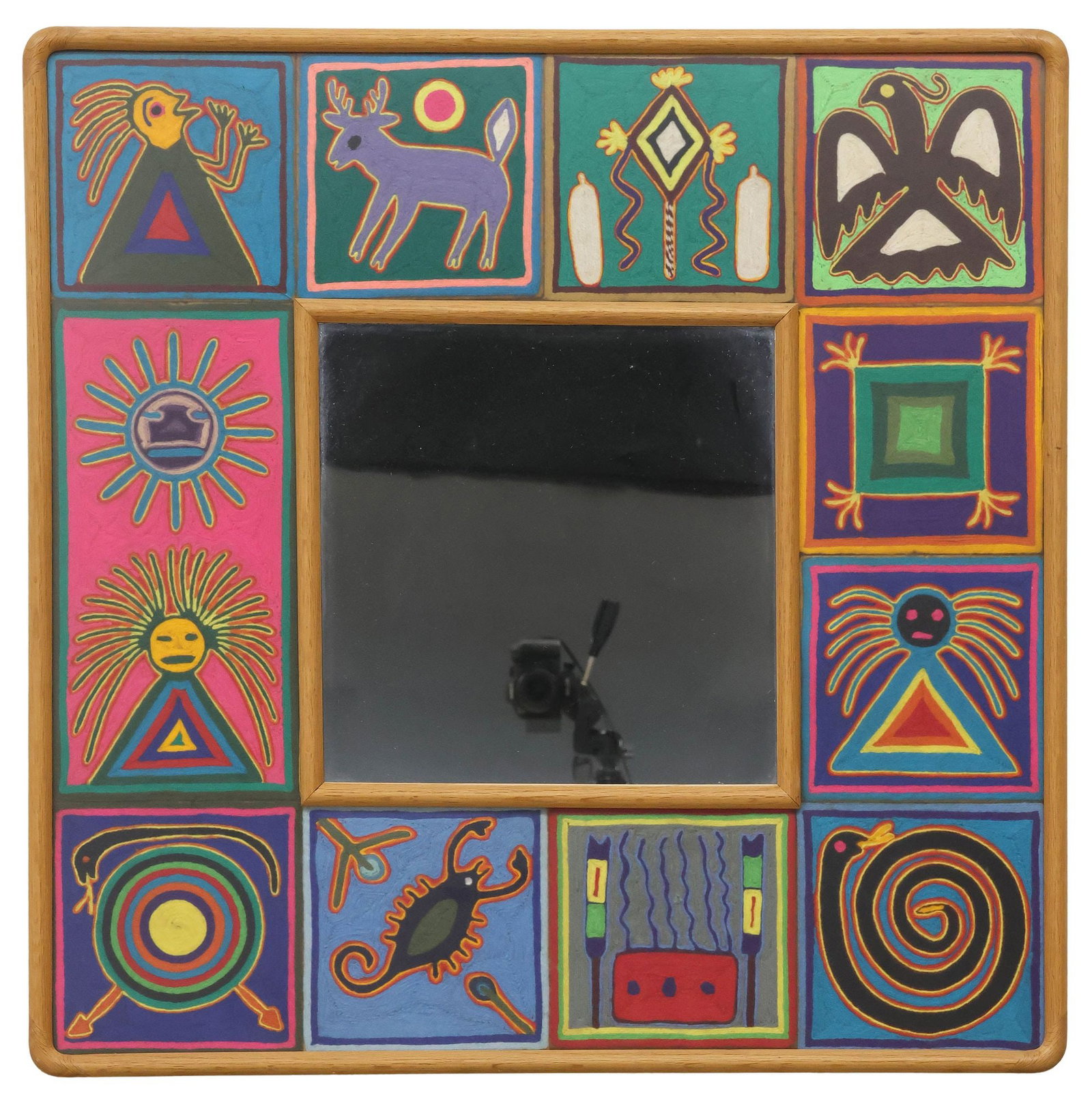 HUICHOL INDIAN FOLK ART YARN PAINTING FRAMED WALL MIRROR: Huichol Indian folk art framed wall mirror, square oak frame housing (twelve) small yarn paintings, depicting various animals, figures, and spiritual motifs, central flat mirror plate, unsigned, sight