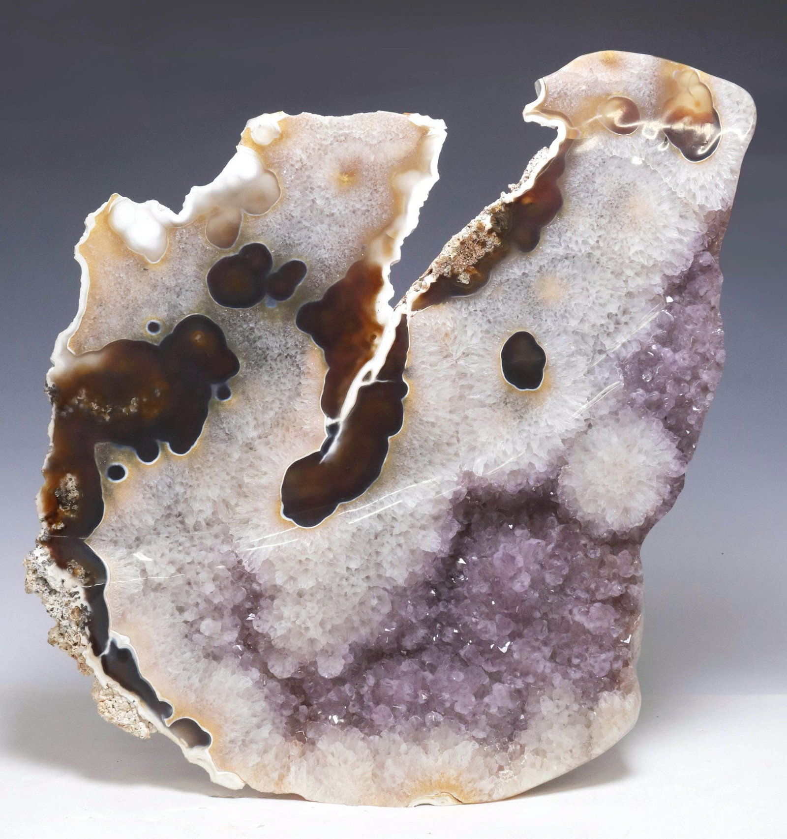 LARGE GEOLOGICAL POLISHED AMETHYST GEODE SLICE, 26.5"H: Large geological polished amethyst geode slice specimen, of organic form, with crystalline and russet inclusions, approx 26.5"h, 22"w, 4.5"d, 59.5lbs **Provenance: Treasures from the vaults of a