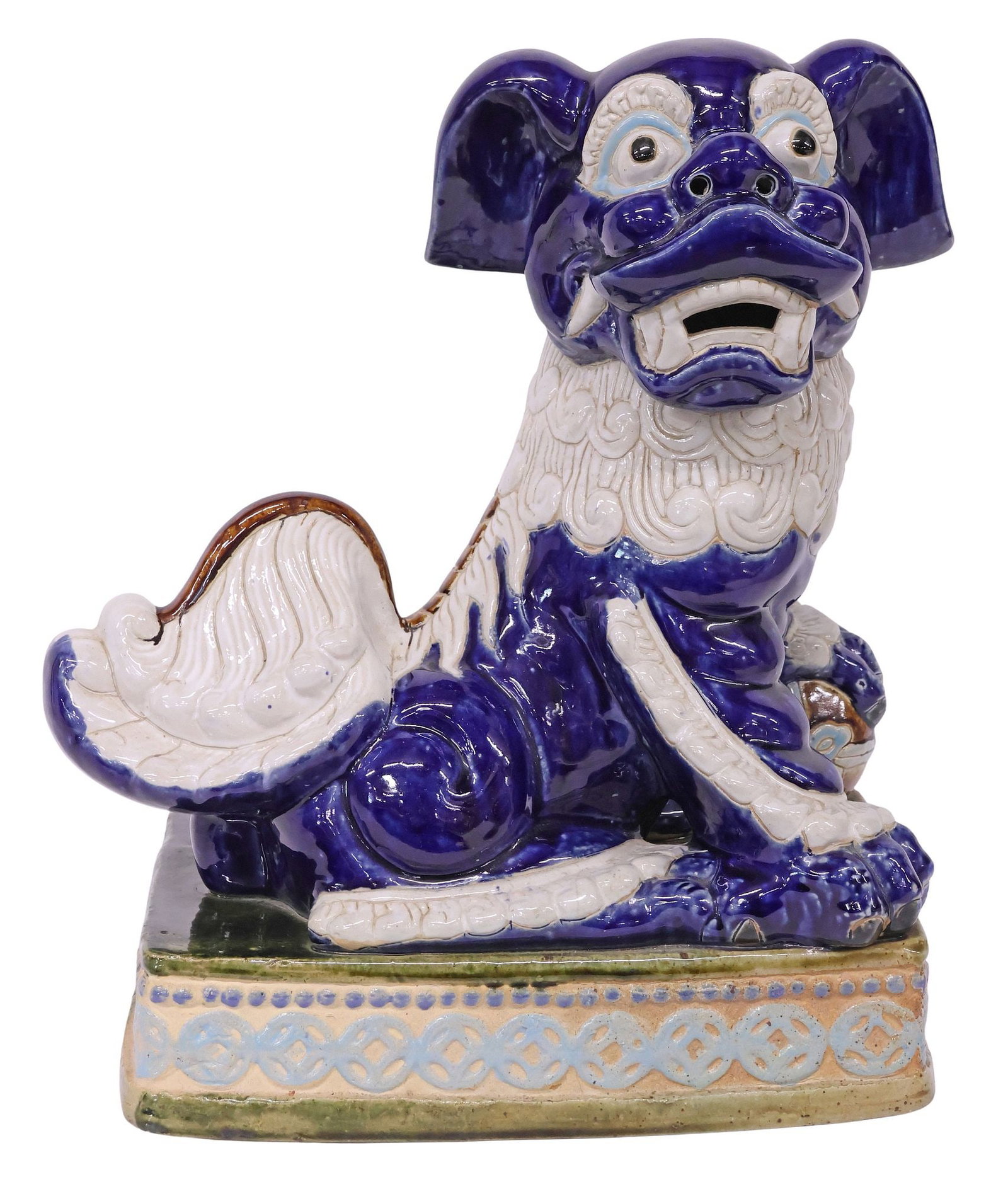 LARGE CHINESE BLUE & WHITE EARTHENWARE FOO LION ON SANCAI BASE, 19.5"H: Large Chinese glazed earthenware figure, modeled as a blue and white seated foo lion with front paw on a ball, rising on a sancai glazed rectangular platform base with lucky coin pattern, front-facing