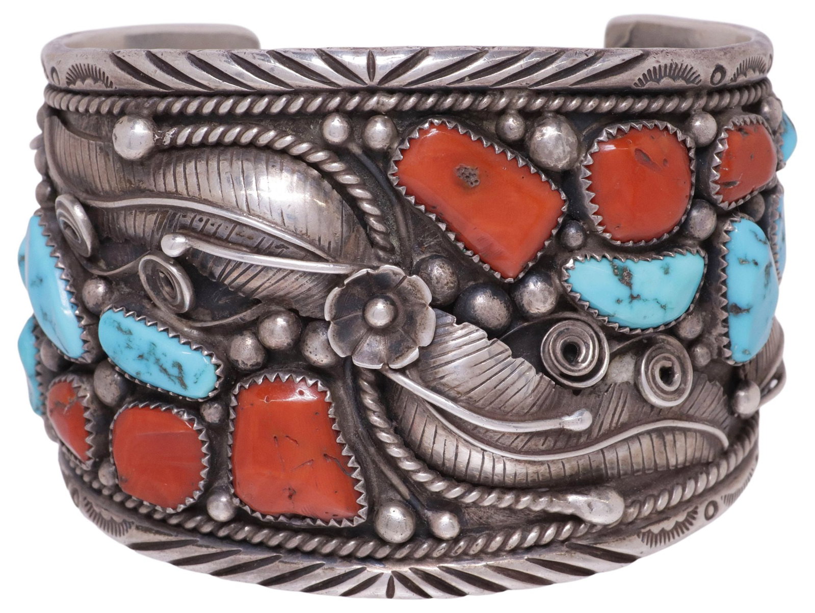 LARGE NATIVE AMERICAN SILVER, TURQUOISE & RED CORAL CUFF BRACELET: Native American silver (content unknown) and gemstone cuff bracelet, with floral and feather motifs, among bezel-set red coral and turquoise cabochons, with stampwork trim, stylized mark, possibly CH,
