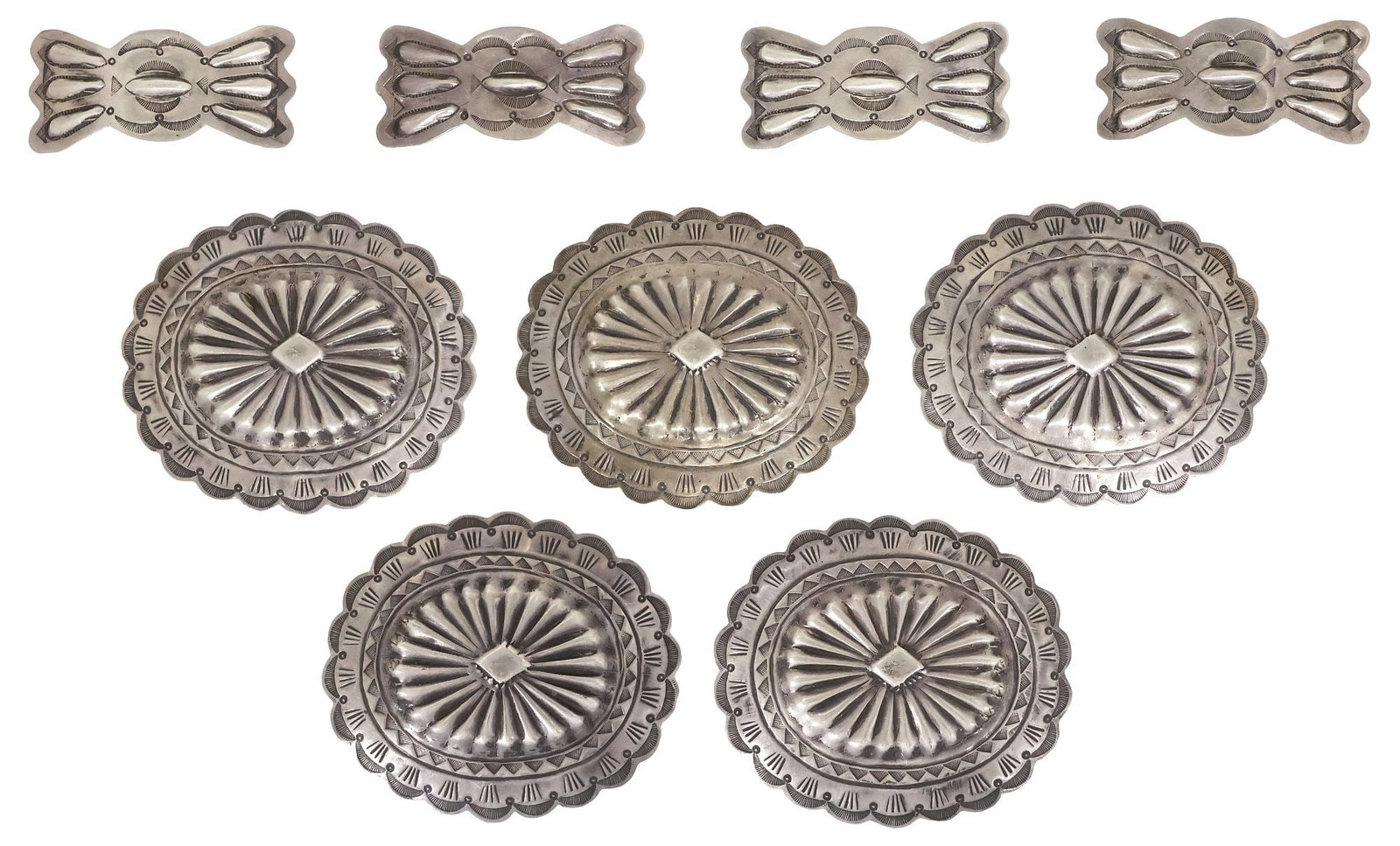 (9) NATIVE AMERICAN REPOUSSE SILVER CONCHOS: (lot of 9) Native American silver (content unknown) conchos, likely Navajo/ Dine, each with repousse lobing and stampwork trim, copper belt slide backs, unmarked, including: (5) oval medallions, appro
