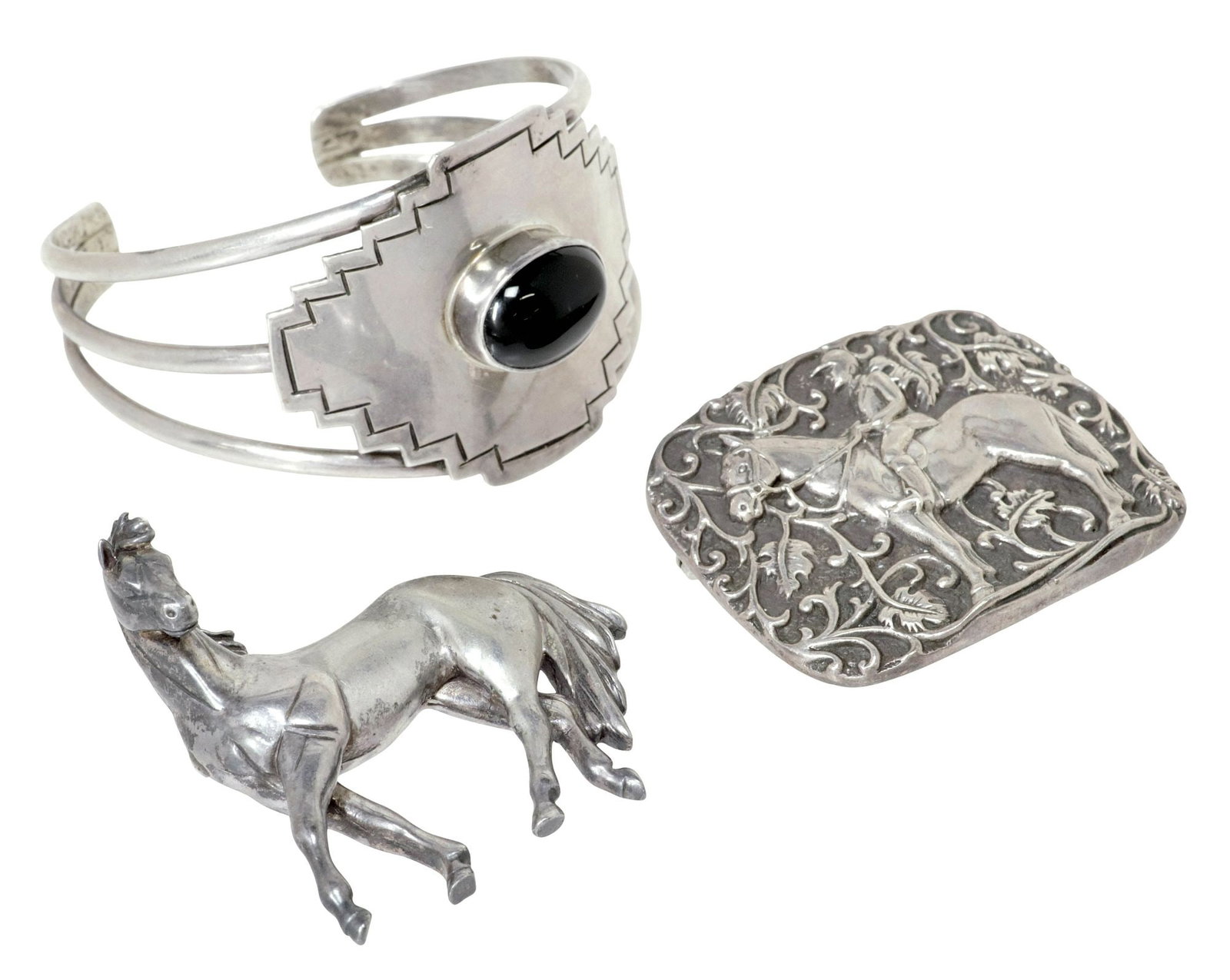 (3) CAROL FELLEY (20TH C.) SOUTHWEST STERLING HORSE BROOCHES & ONYX CUFF: (lot of 3) Southwest sterling silver jewelry set, Carol Felley (New Mexico, 20th c.), marked sterling with maker's mark at reverse, including: (1) cuff bracelet, dated [19]88, central ovular onyx cabo