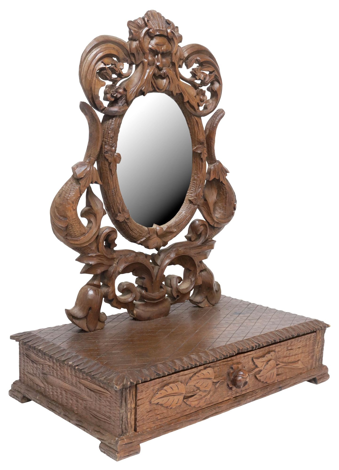 BLACK FOREST STYLE FIGURAL & FOLIATE CARVED WALNUT VANITY MIRROR: Black Forest style carved walnut tabletop vanity/ dressing mirror, 20th c., having ovular scrolling foliate frame surmounted by a figural mask, encasing flat mirror plate, over single drawer with foli