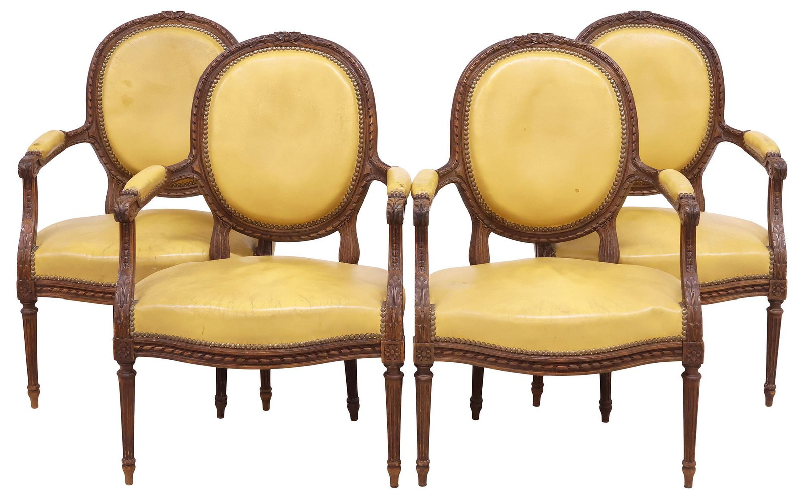(4) FRENCH LOUIS XVI STYLE LEATHER-UPHOLSTERED WALNUT ARMCHAIRS: (lot of 4) French Louis XVI style carved walnut armchairs/ fauteuils, late 19th c., each having foliate ribbon crest, above oval medallion back and padded seat in worn yellow leather upholstery, with 