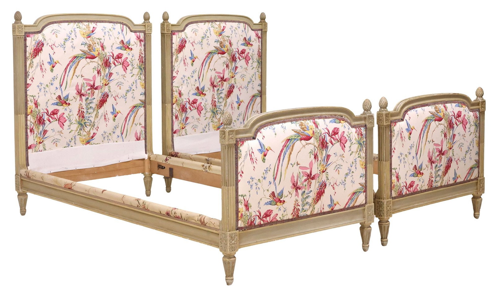 (2) FRENCH LOUIS XVI STYLE PAINTED & UPHOLSTERED BEDS: (pair) French Louis XVI style paint-decorated beds, early 20th c., each having arched headboard and footboard in a worn painted finish, framed by pineapple finials and fluted posts, in patterned