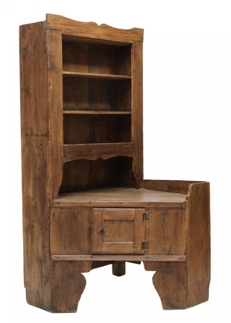 PRIMITIVE PINE CORNER CUPBOARD & DISPLAY: Primitive pine corner cupboard, 19th c., joined with pegs and squared nails, an open work surface with a rising display / storage shelf at one side, a lower front door, rising on wide shaped legs and 