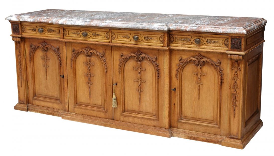 FRENCH MARBLE TOP BREAKFRONT SIDEBOARD: French breakfront sideboard, c. 1920, a shaped marble top over four frieze drawers, each divided and felt lined, four front doors decorated with applied foliate carving, rising on the conforming stepp