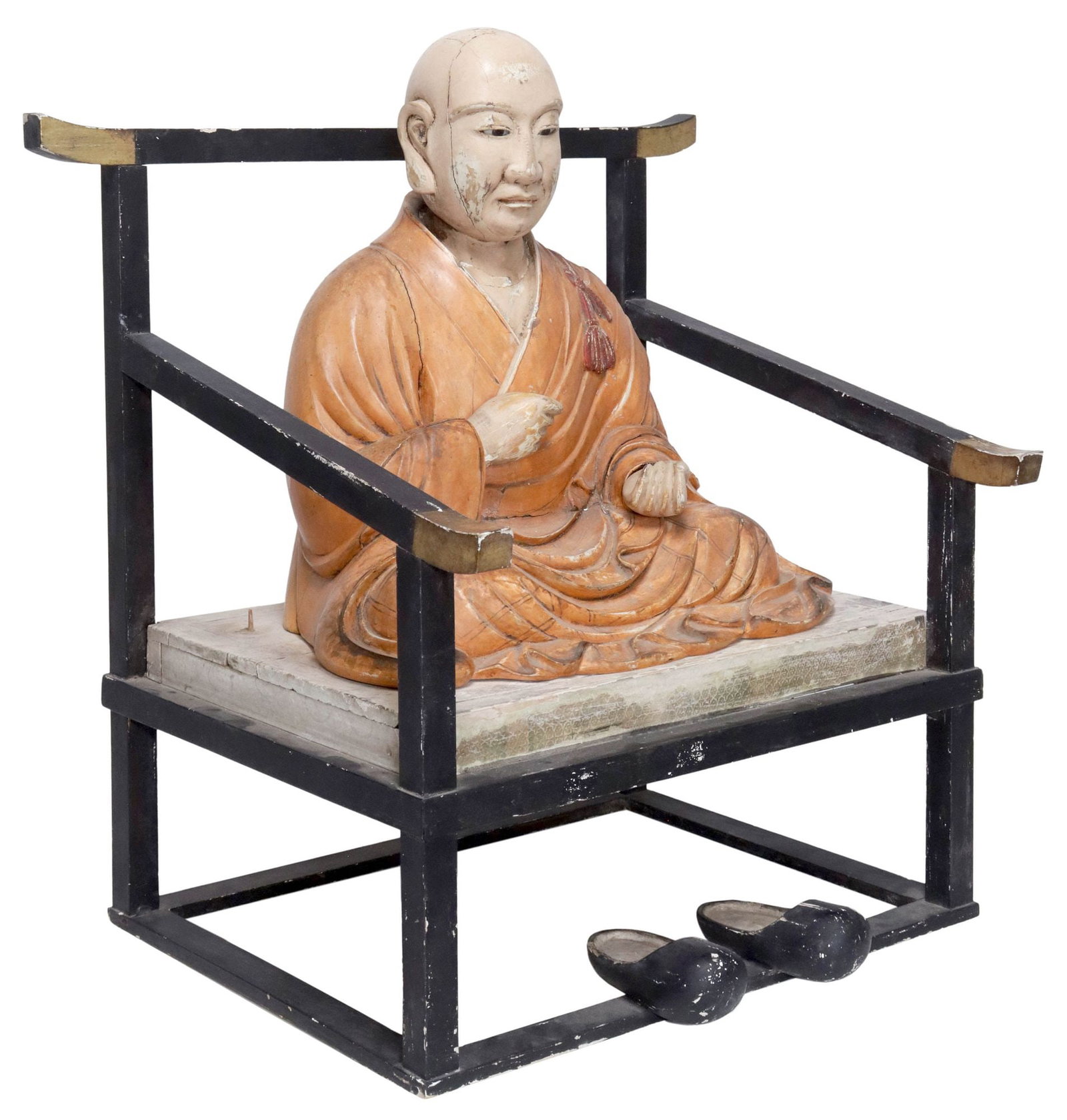 JAPANESE CARVED & LACQUERED MONK FIGURE OF KUKAI ON MEDITATION CHAIR: Japanese carved and lacquered wood figural sculpture, modeled as the Buddhist monk Kukai (Kobo Daishi, Japanese, c.774-835), with inset glass eyes, in orange robes with red tassels, the hands in a gri