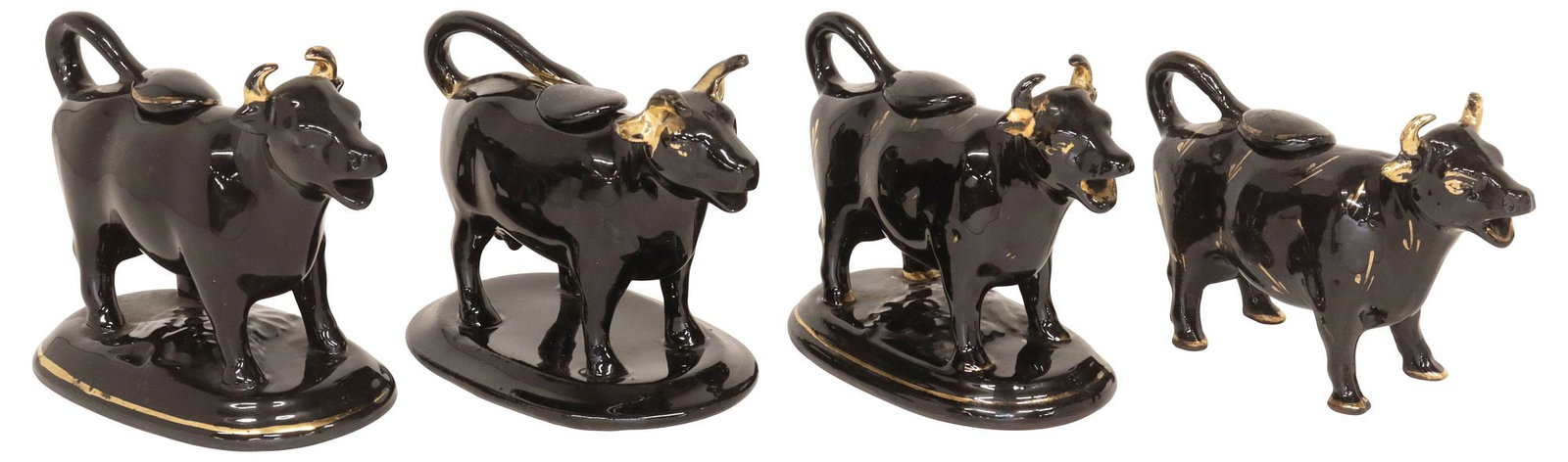 (4) ENGLISH STAFFORDSHIRE JACKFIELD GLAZE COW CREAMERS: (lot of 4) English Staffordshire cow creamers, 20th c., each in a Jackfield black glaze, with parcel-gilt features, including: (3) rising on ovular base, largest: approx 4.75"h, 6.25"w, 3.5"d; (1) fre