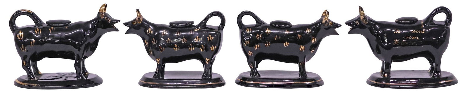 (4) ENGLISH STAFFORDSHIRE JACKFIELD GLAZE COW CREAMERS: (lot of 4) English Staffordshire cow creamers, 20th c., each in a Jackfield black glaze, with parcel-gilt features, rising on ovular base, (one) with inscription "A Present from Holywell," (one) with 
