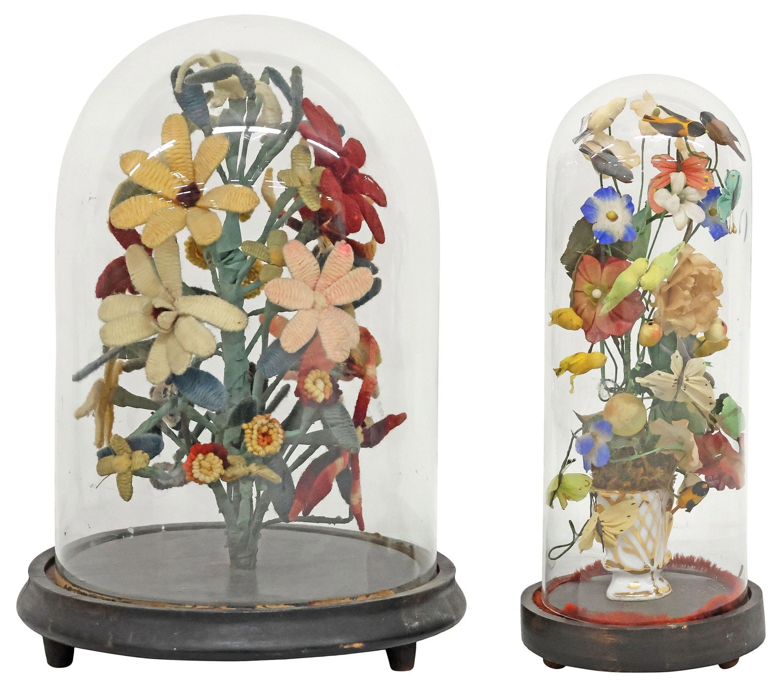 (2) VICTORIAN GLASS CLOCHE GARNITURES, NEEDLEWORK & SILK FLOWERS: (lot of 2) Victorian cloche mantel garnitures, late 19th c., glass cloche/ dome on ebonized base, enclosing floral bouquet, including: (1) with polychrome needlework flowers on wrapped wire stem, over