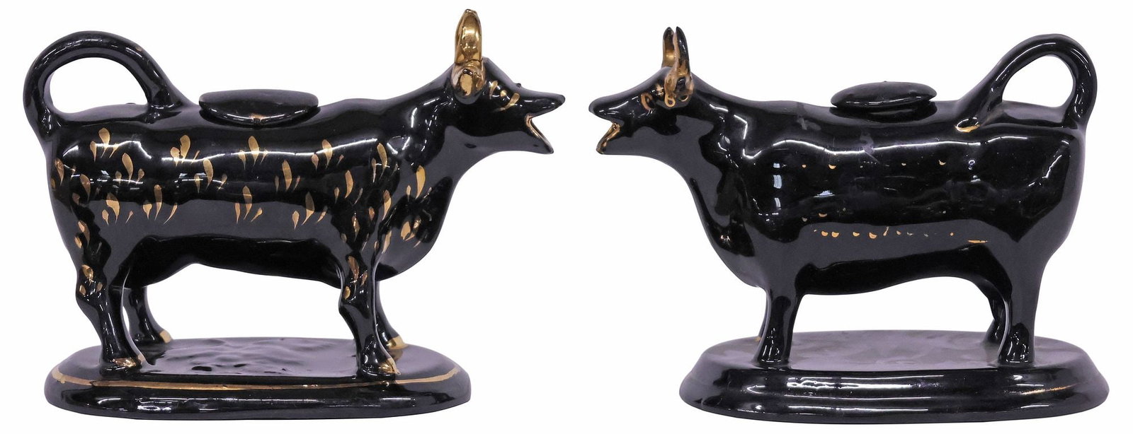 (2) ENGLISH STAFFORDSHIRE JACKFIELD GLAZE COW CREAMERS: (lot of 2) English Staffordshire cow creamers, 20th c., each in a Jackfield black glaze, with parcel-gilt features, rising on ovular base, restoration to horns, largest: approx 5.5"h, 7 5/8"w, 4"d, 2l