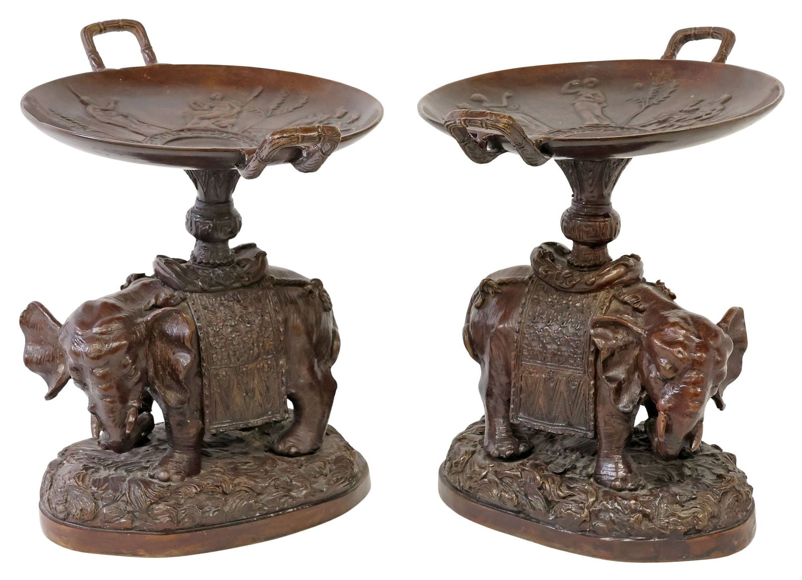 (2) MAITLAND-SMITH PATINATED BRONZE ELEPHANT TAZZAS: (pair) Patinated bronze tazzas, Maitland-Smith, 20th c., with Neoclassical figures in relief, rising on full-figure elephants, adorned in ceremonial garments, on naturalistic base, retaining adhesive 