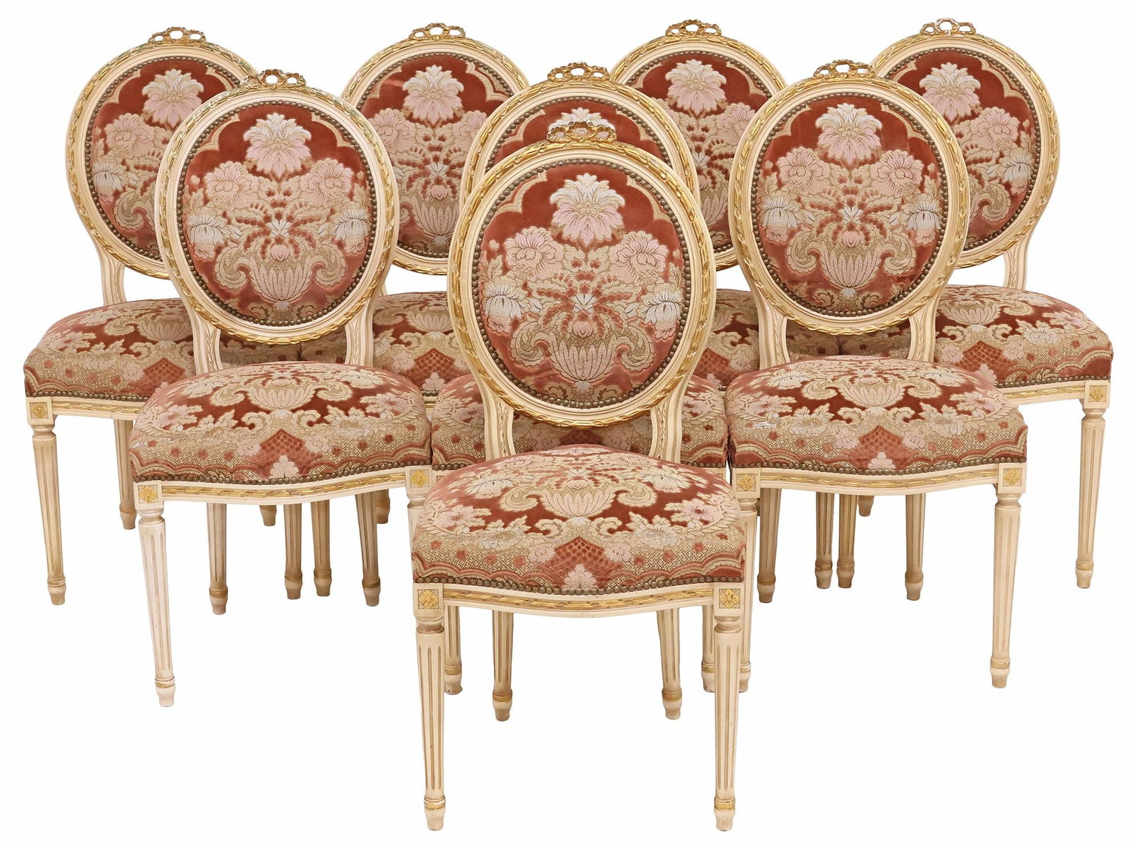 (8) FRENCH LOUIS XVI STYLE PARCEL-GILT & PAINTED DINING CHAIRS: (lot of 8) French Louis XVI style parcel-gilt dining chairs, early 20th c., each in a later cream-painted finish, having molded ribbon bow crest, over oval medallion back and padded seat in floral jac