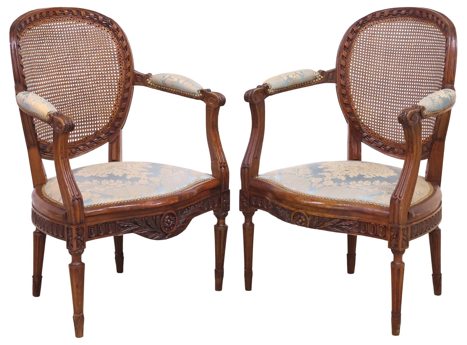 (2) FRENCH LOUIS XVI STYLE SILK-UPHOLSTERED & CANED ARMCHAIRS: (pair) French Louis XVI style walnut armchairs/ fauteuils, 19th c., caned oval medallion back with ribbon twist trim, padded seat and armrests in silk damask upholstery, with nail-head trim, on fluted