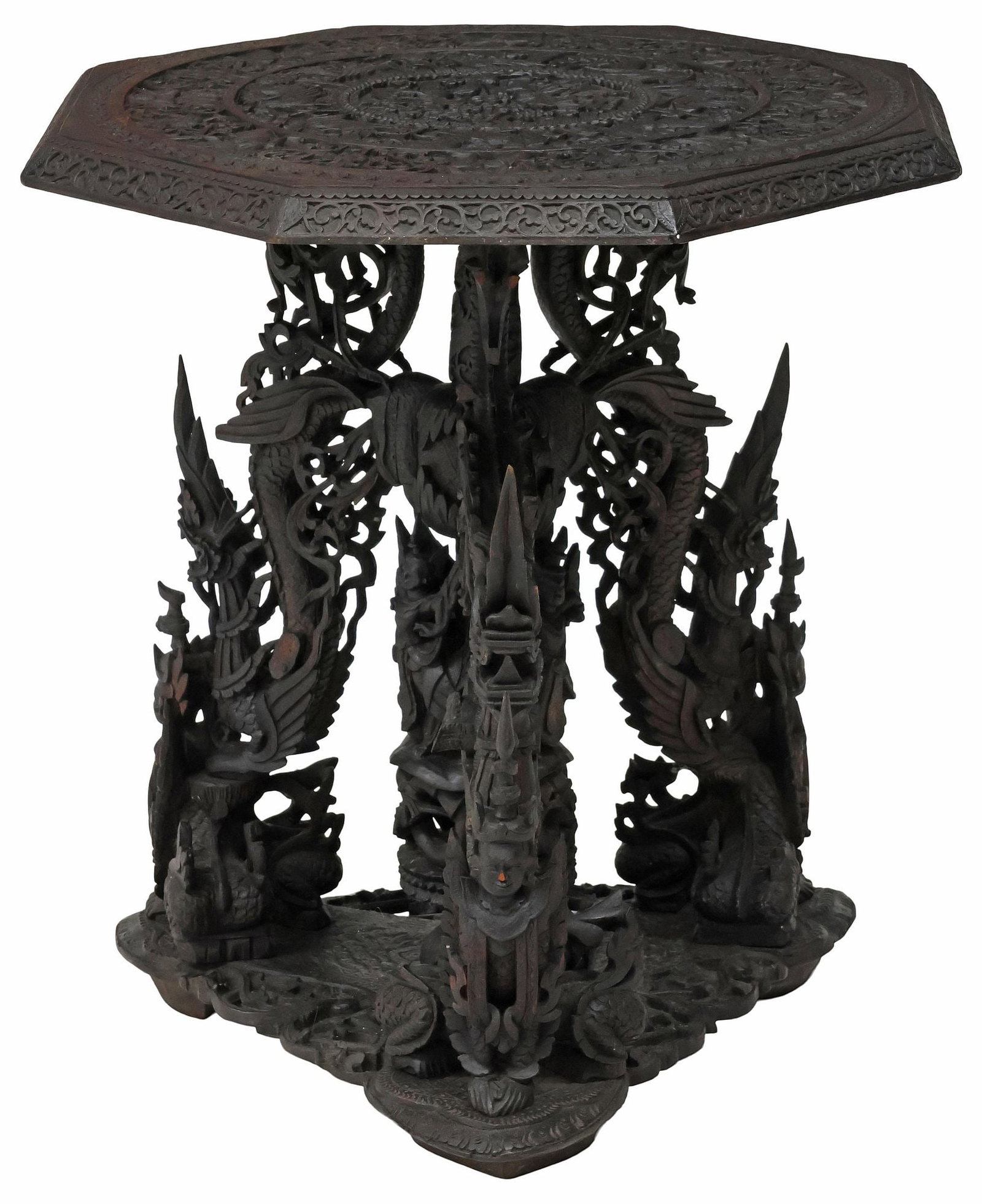 SOUTHEAST ASIAN ORNATELY-CARVED HARDWOOD SIDE TABLE: Southeast Asian carved hardwood side table, possibly Burmese for the Thai market, having octagonal tabletop with central figures among foliated scrollwork in relief, rising on figural and serpentine s